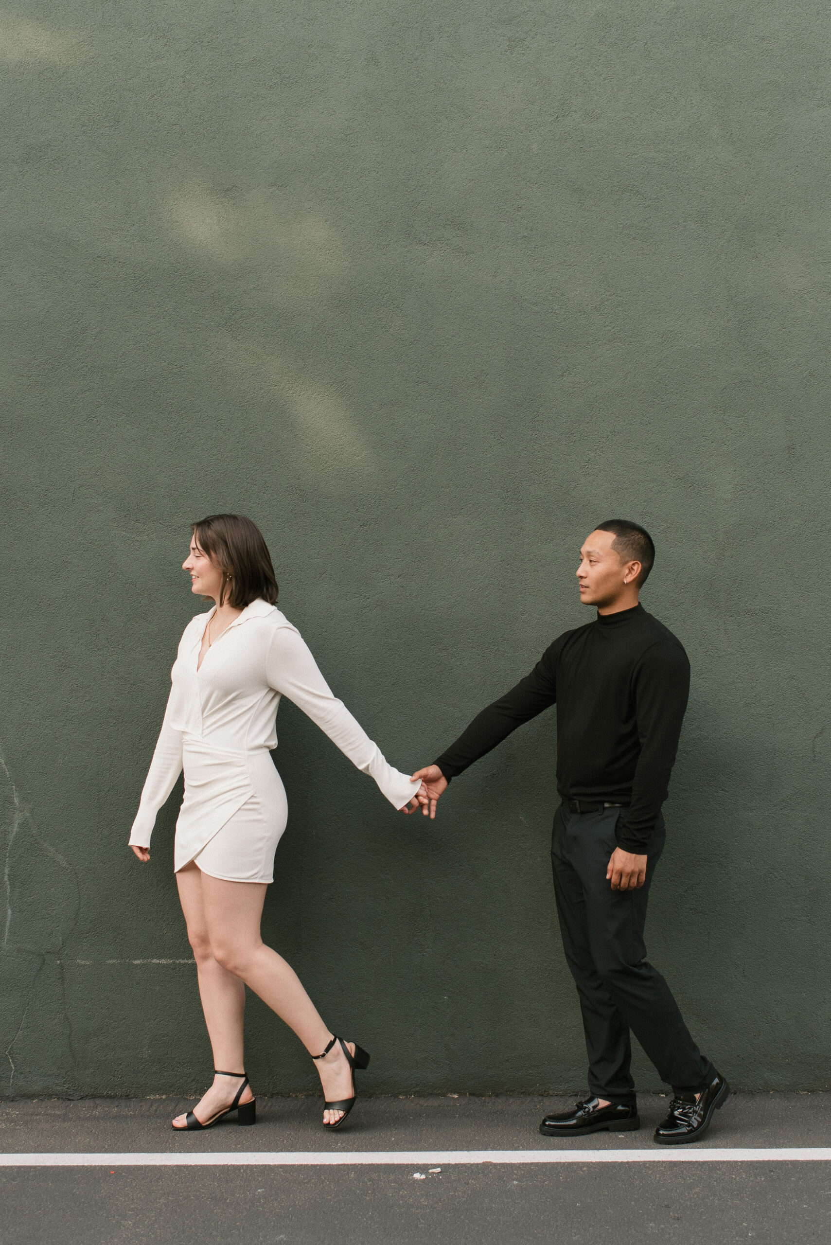 couple against green wall holding hands