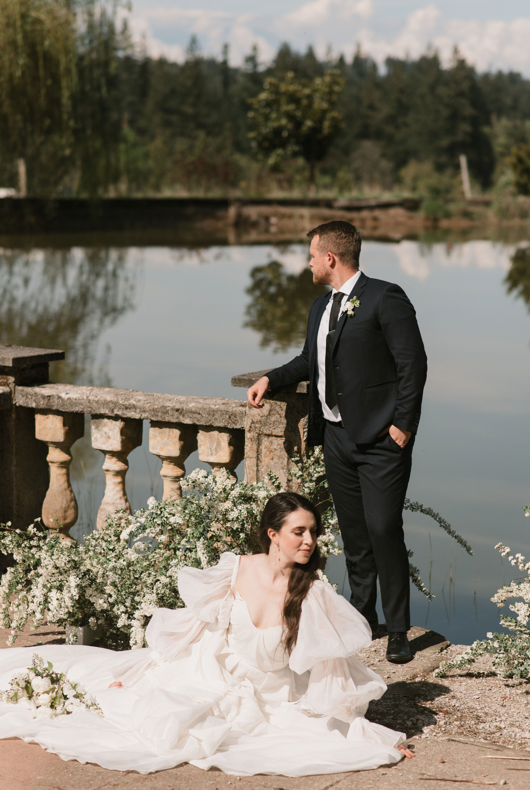 bride and groom posing by the water at european-inspired wedding venue 