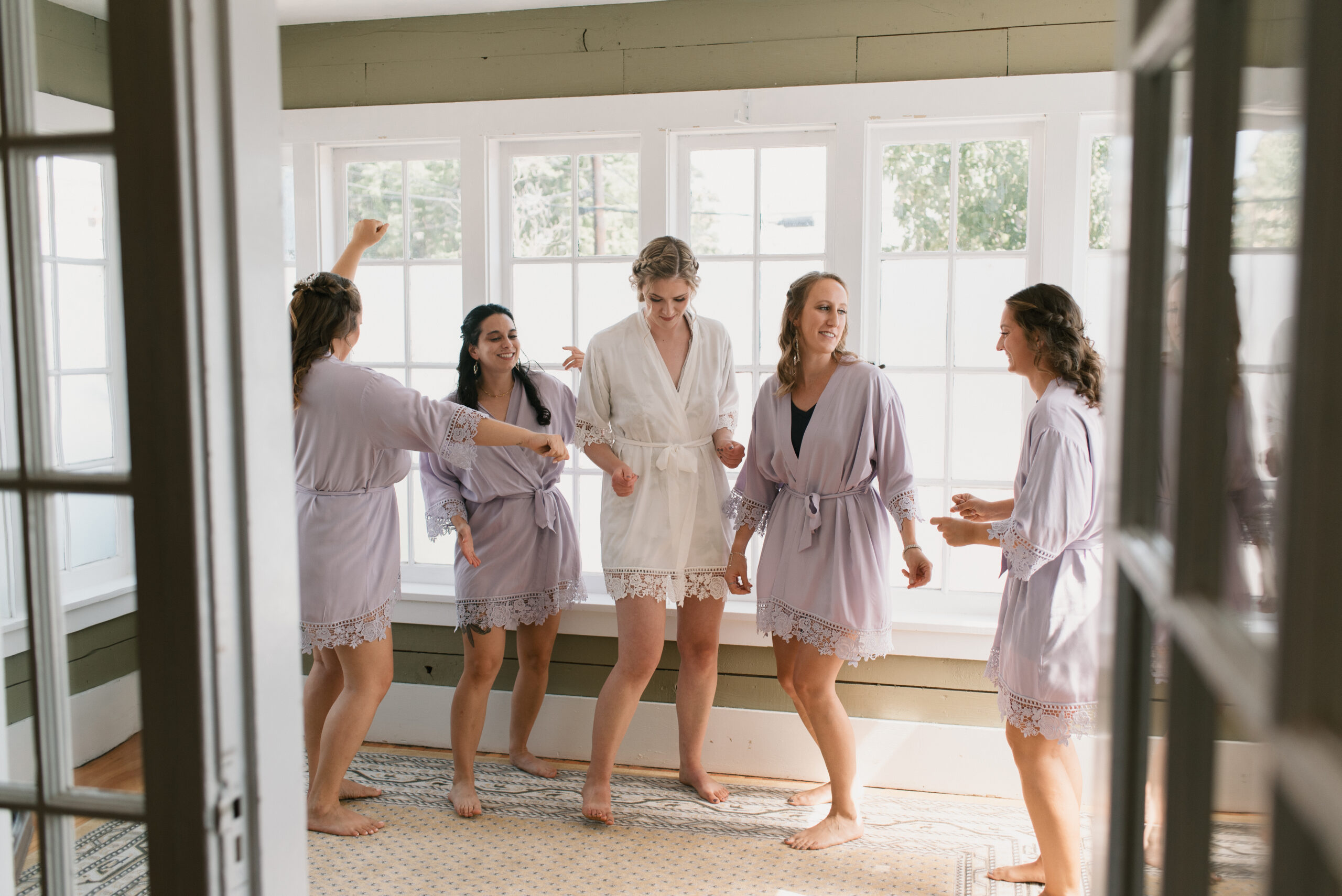 candid wedding photography of bride and bridesmaids dancing while getting ready