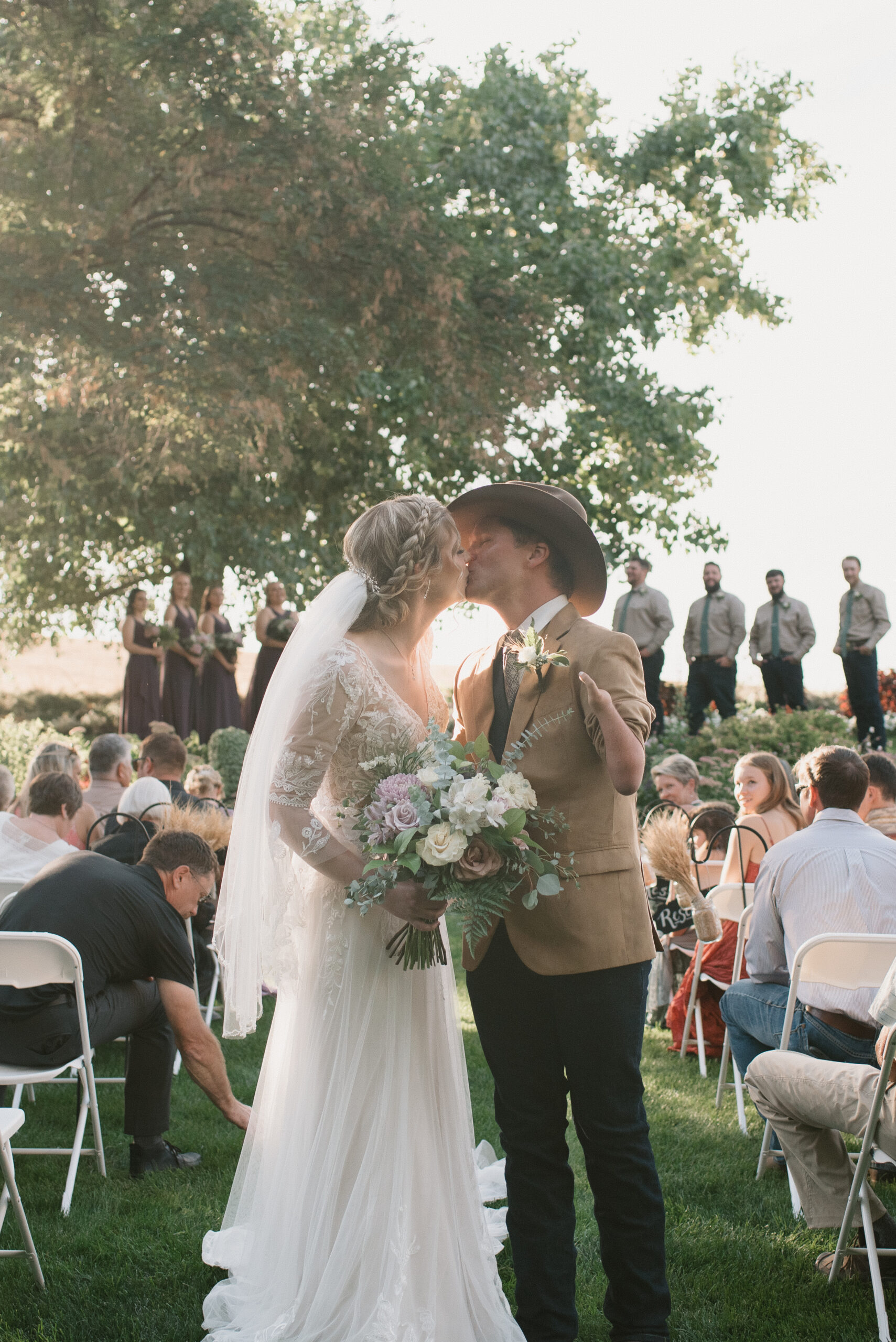 bride and groom kissing in ceremony aisle 