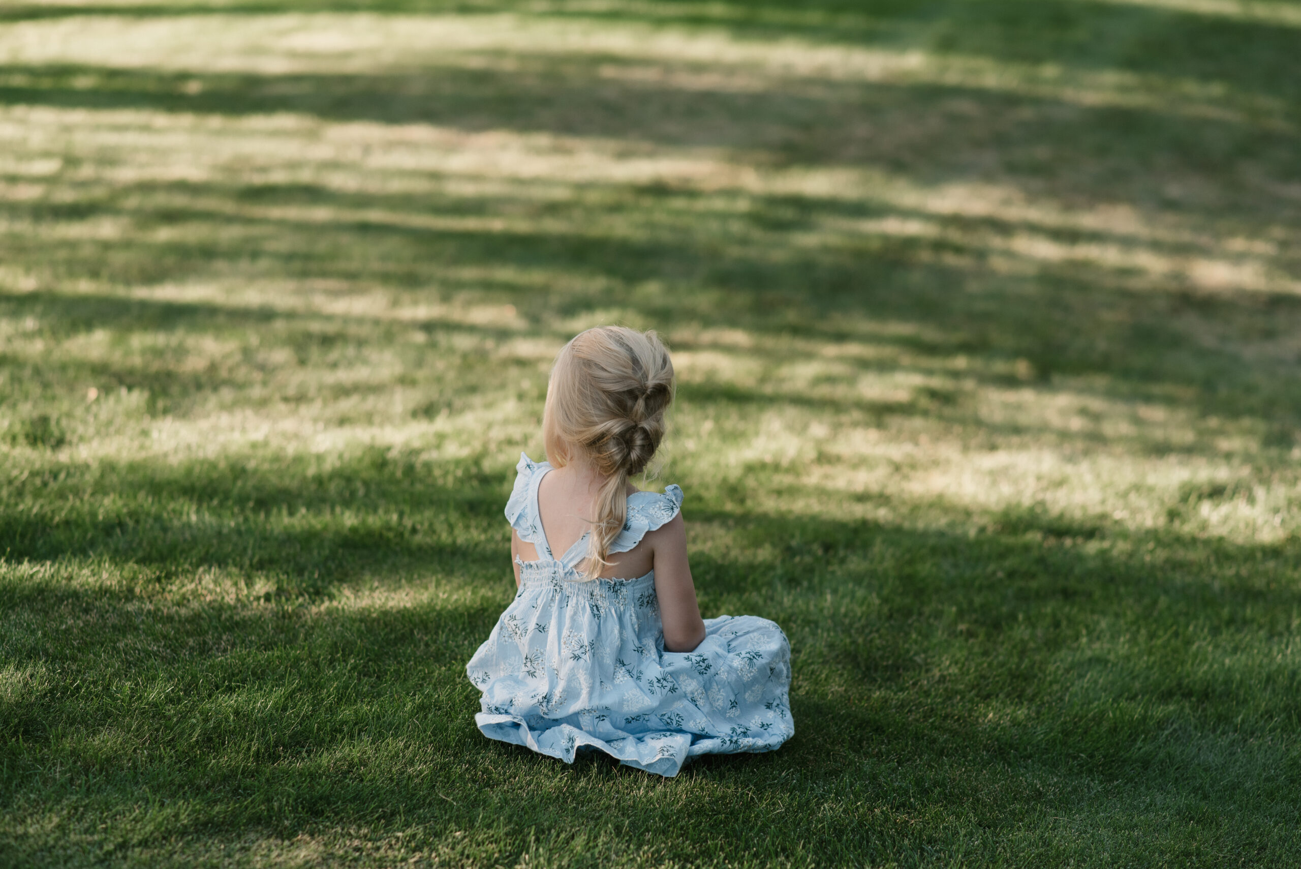 candid wedding photography of a little girl sitting in the grass
