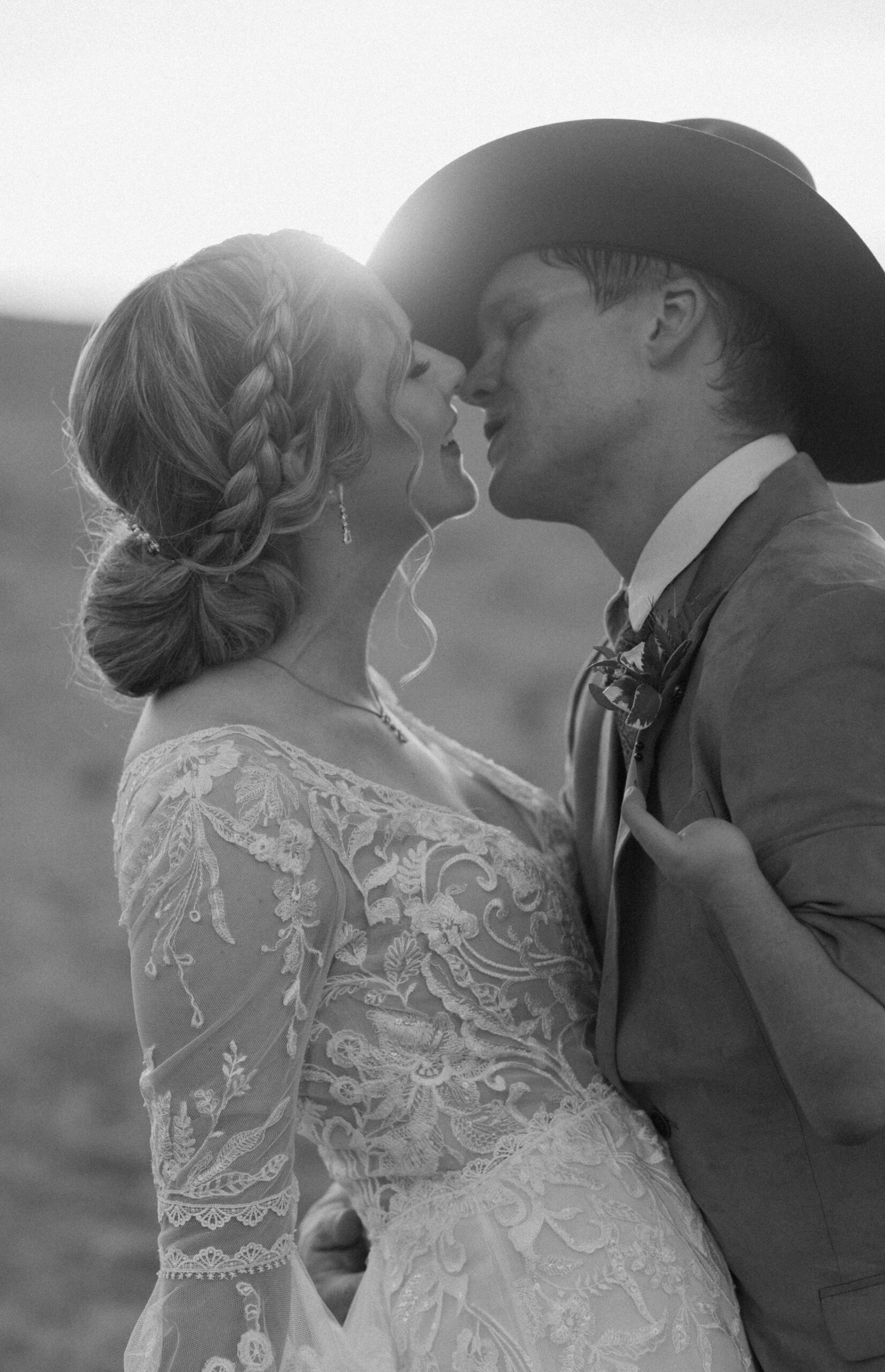 black and white candid wedding photography of bride and groom about to kiss