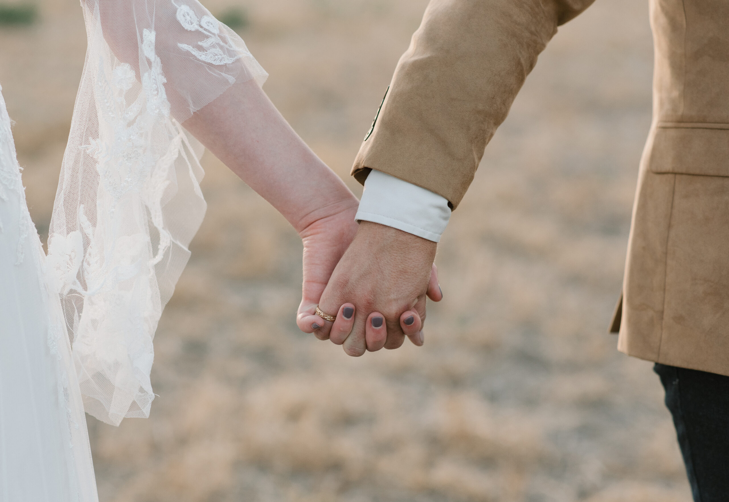 close up of bridal couple holding hands 