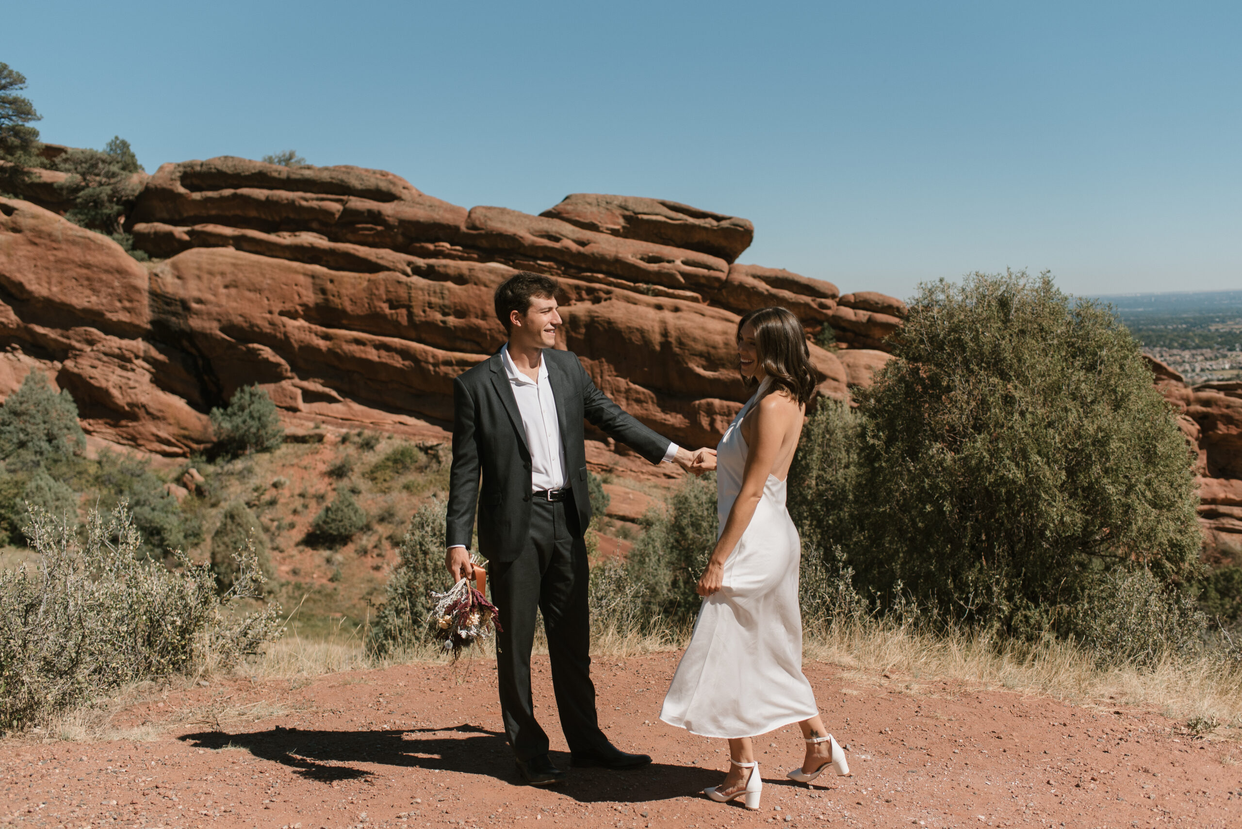 bridal couple holding hands with red rock background