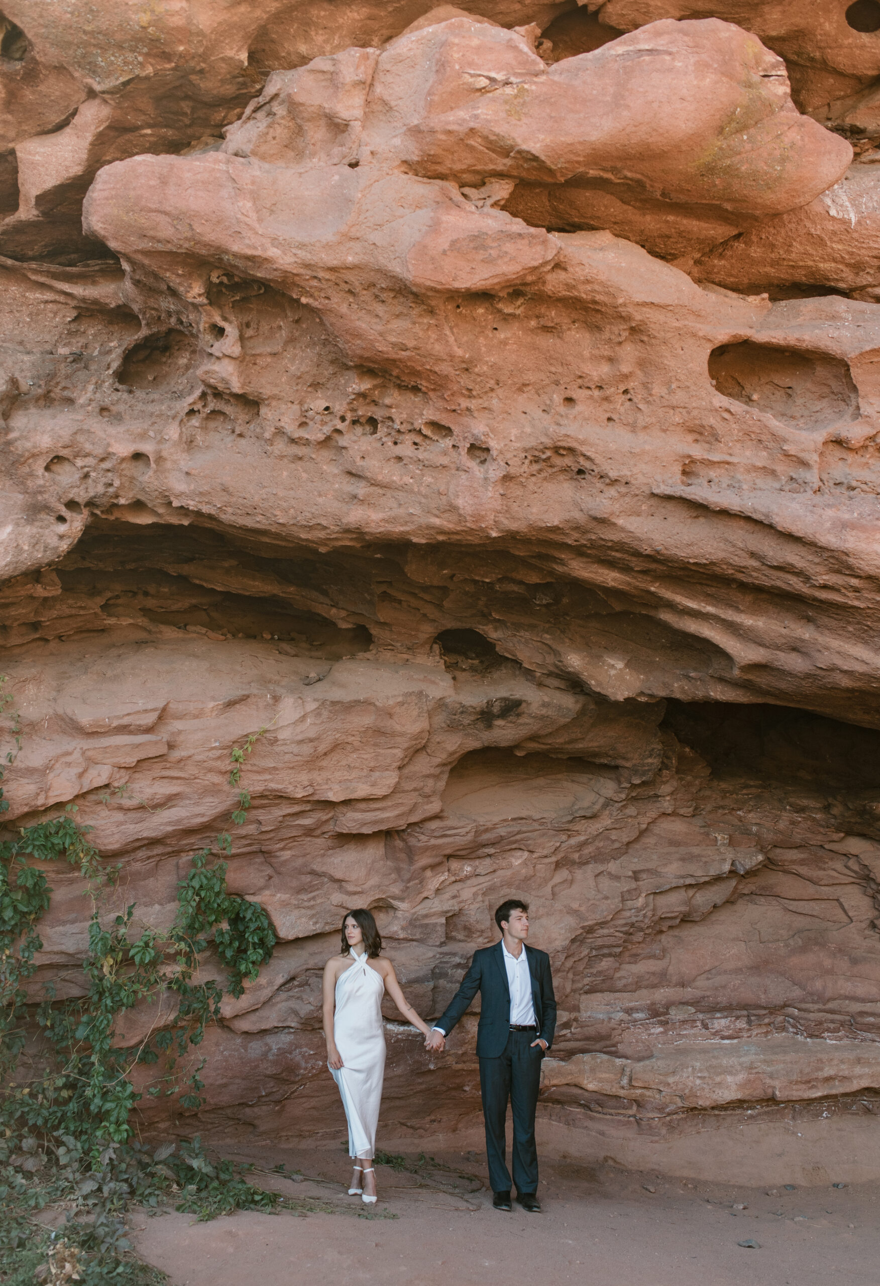 bridal couple holding hands in front of red rocks at Colorado elopement 
