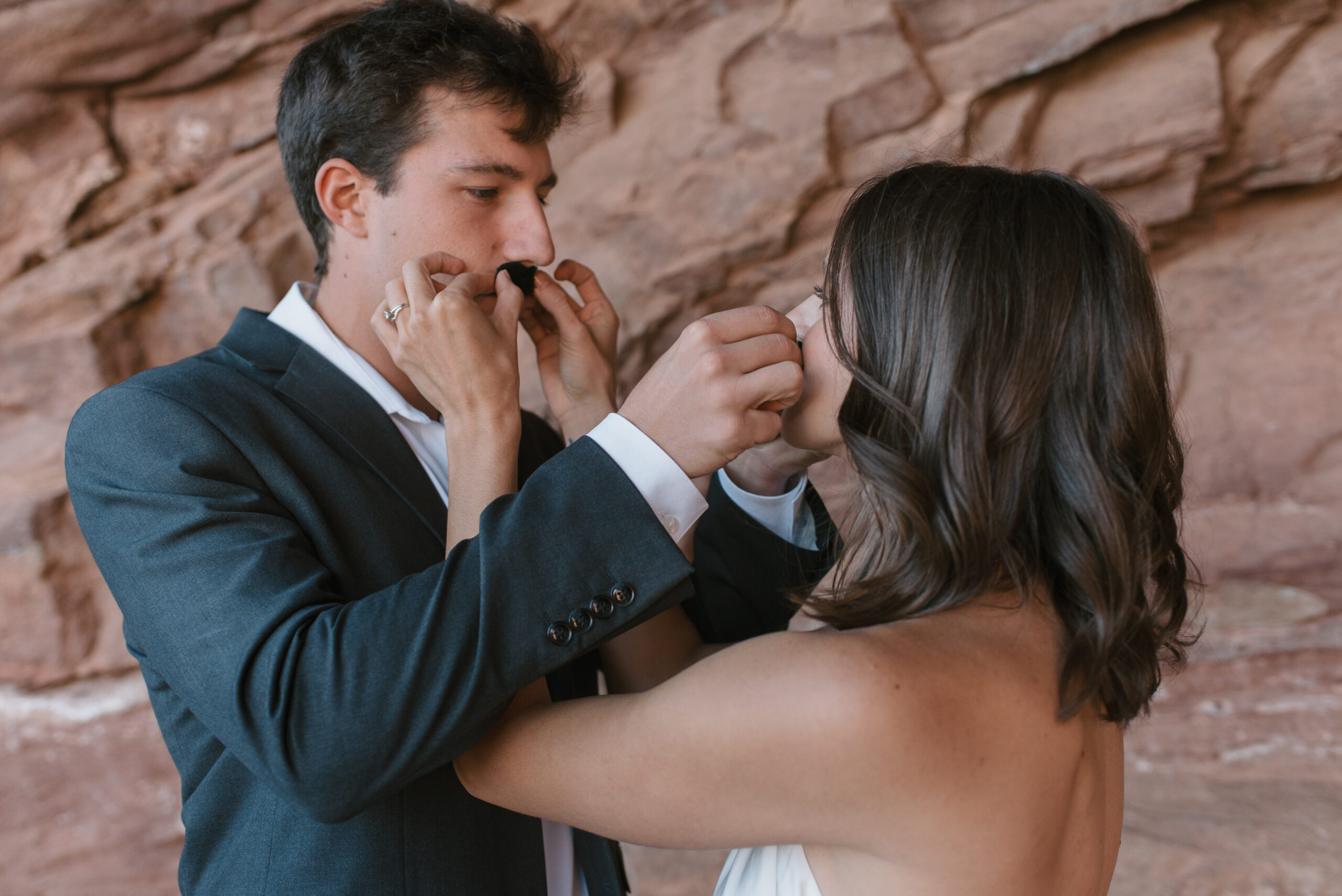 bridal couple putting fake mustaches on each other at colorado elopement