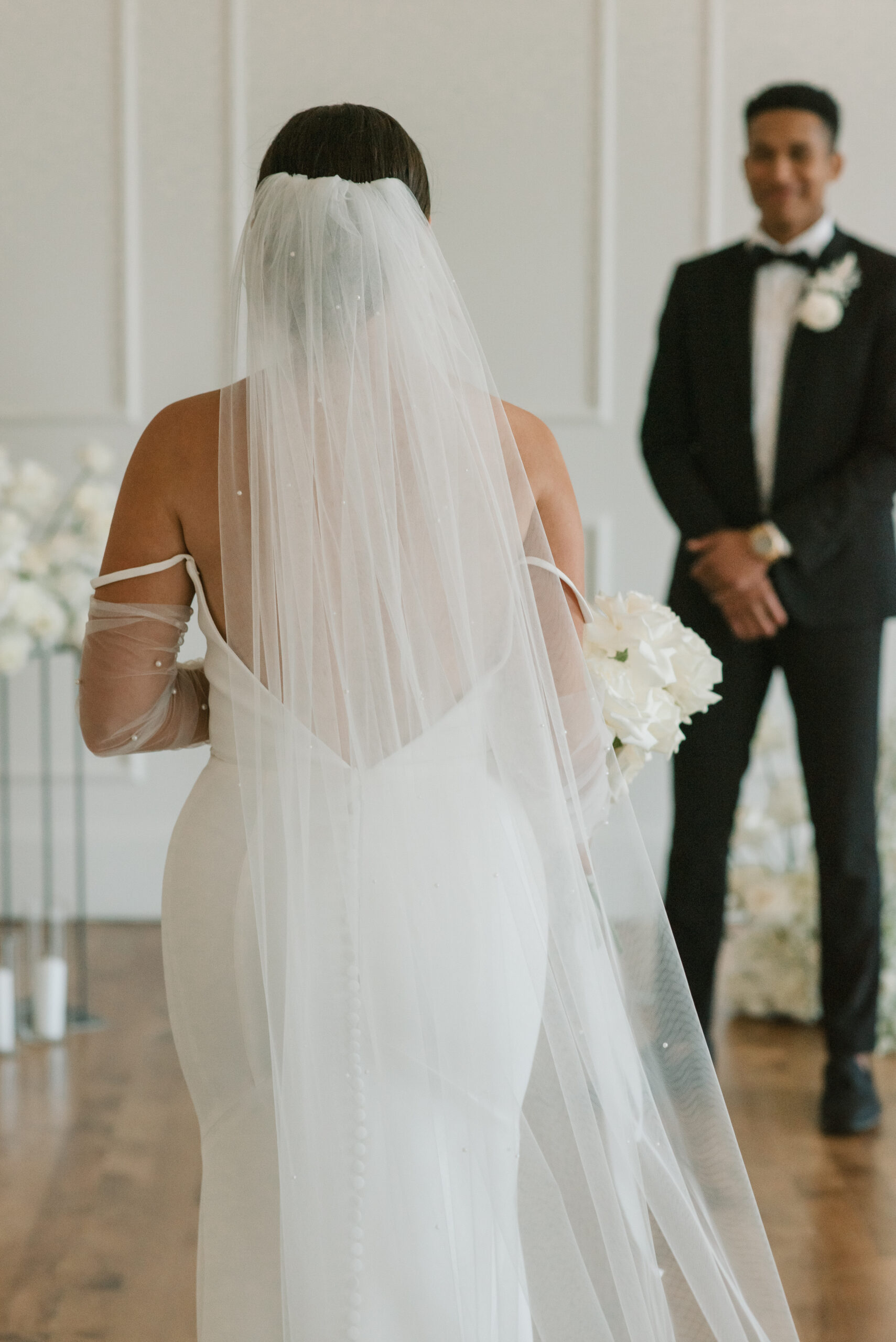 bride walking down the aisle from the back with groom out of focus