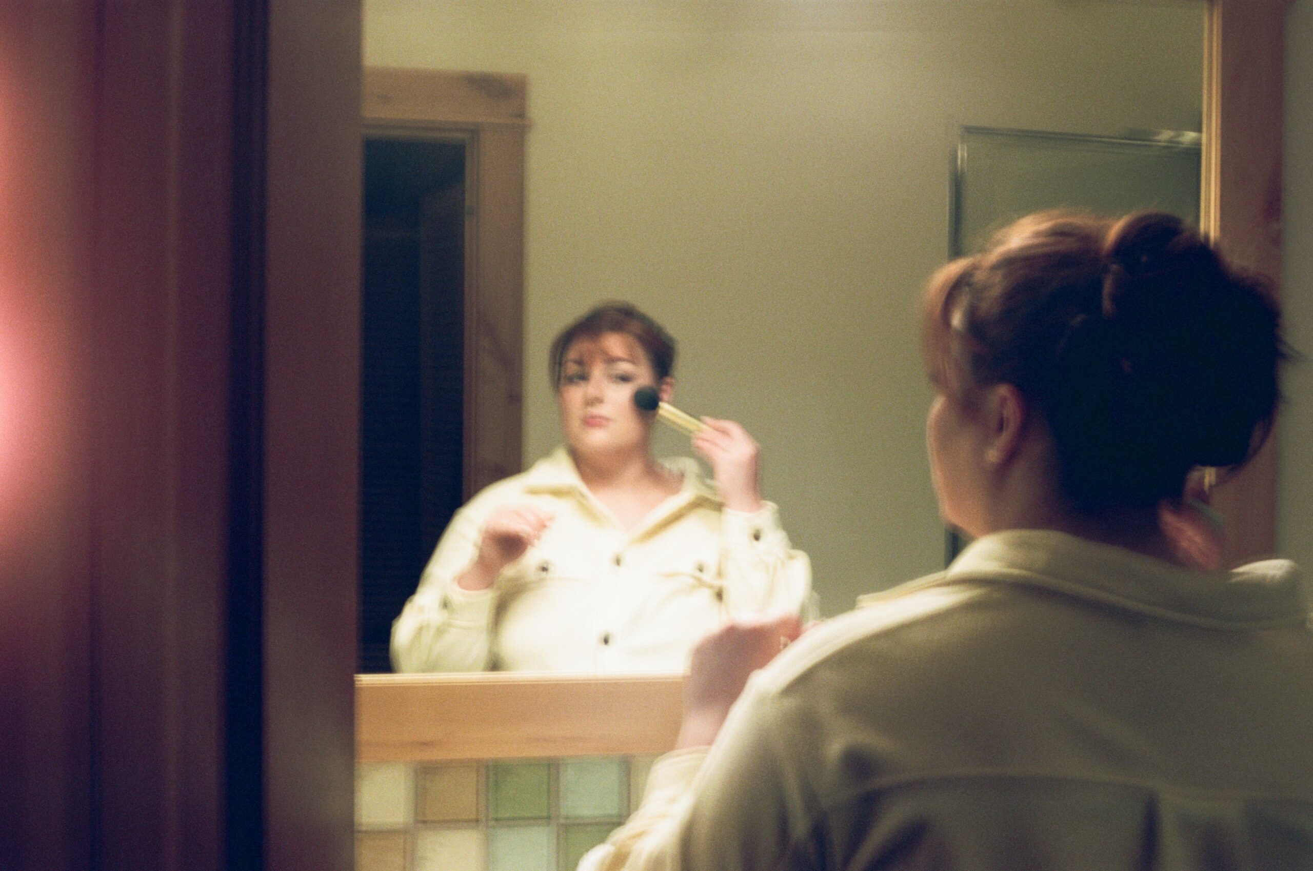 wedding film photography of bride getting ready in the mirror 