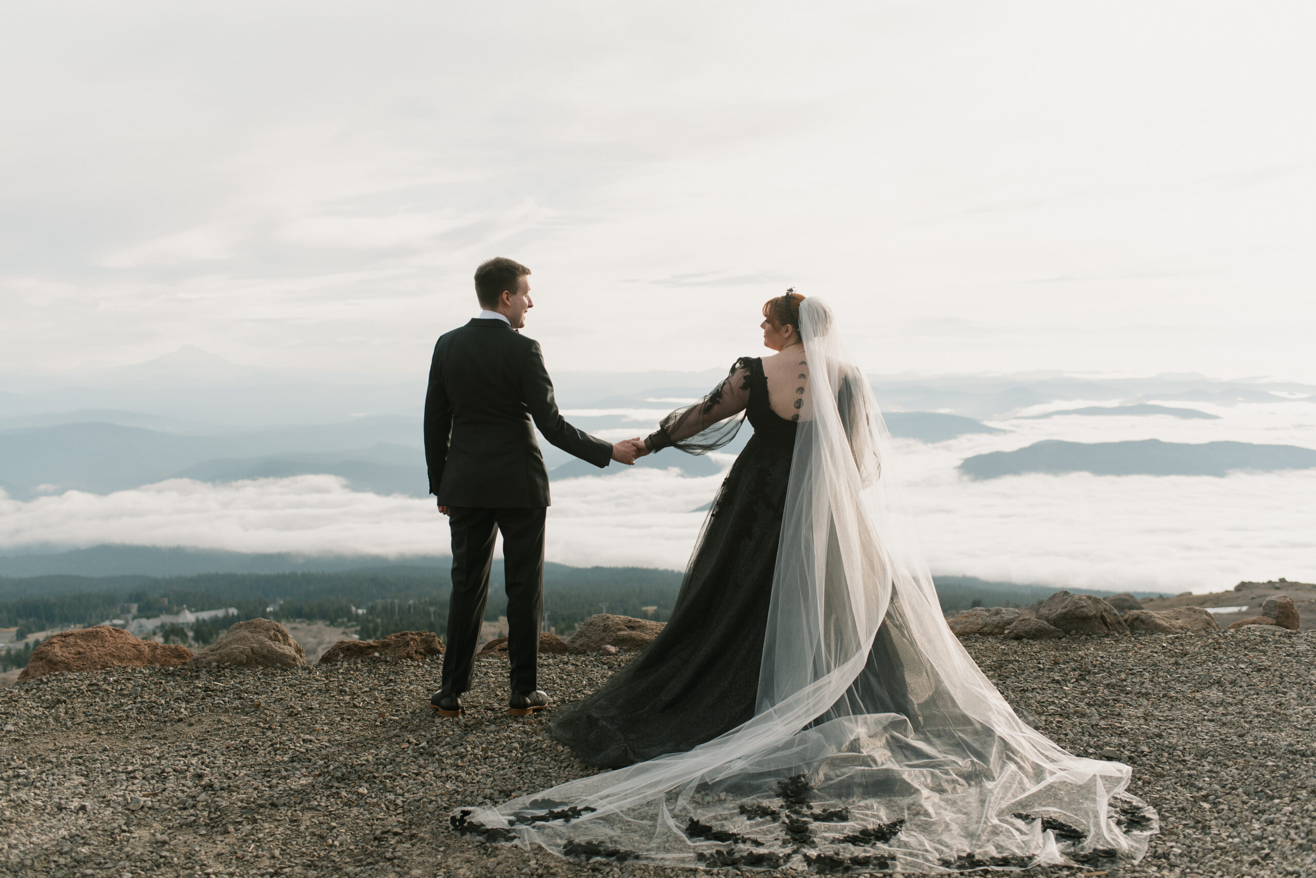 bride and groom holding hands on top of mount hood