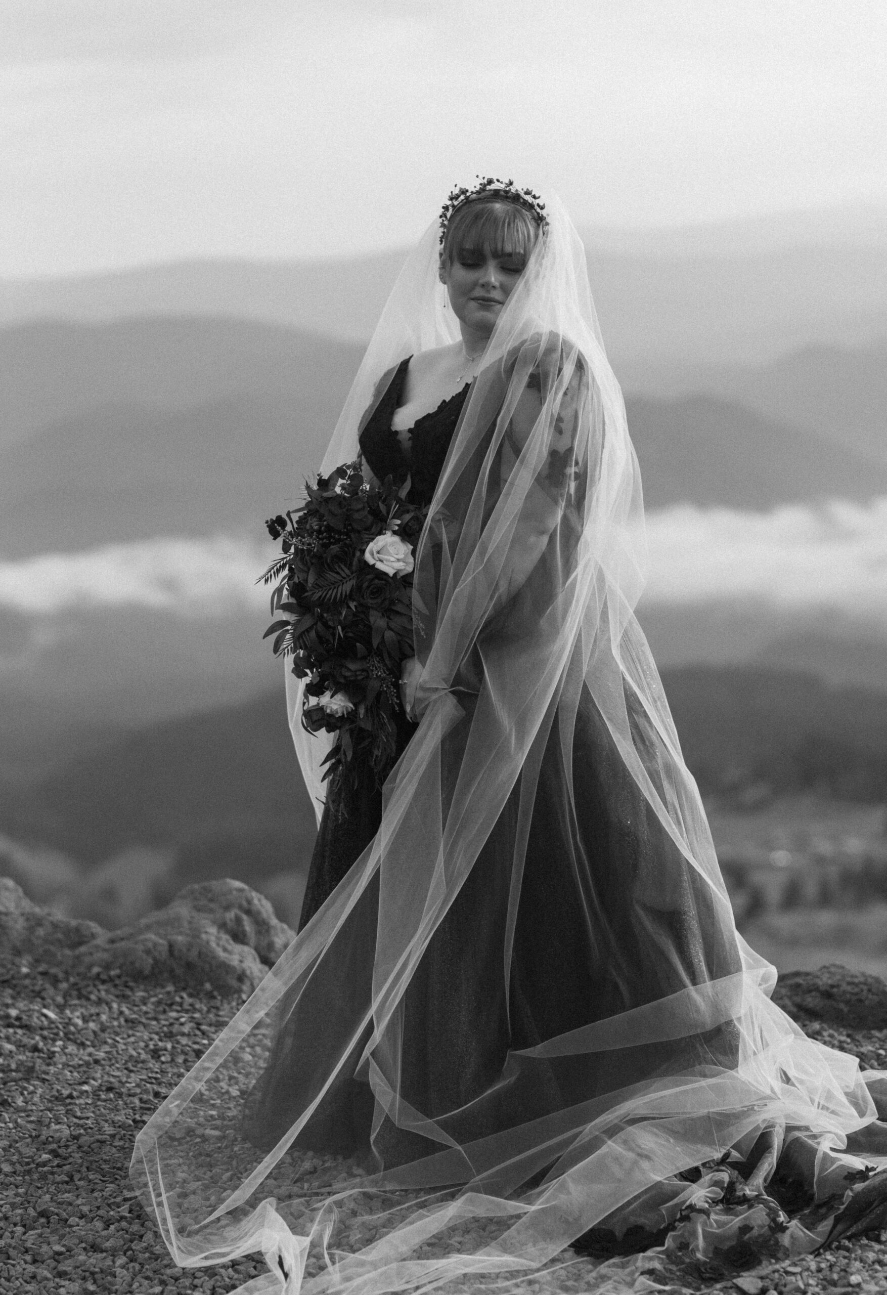 black and white of bride in black dress with veil on top of mt hood at small unique wedding 