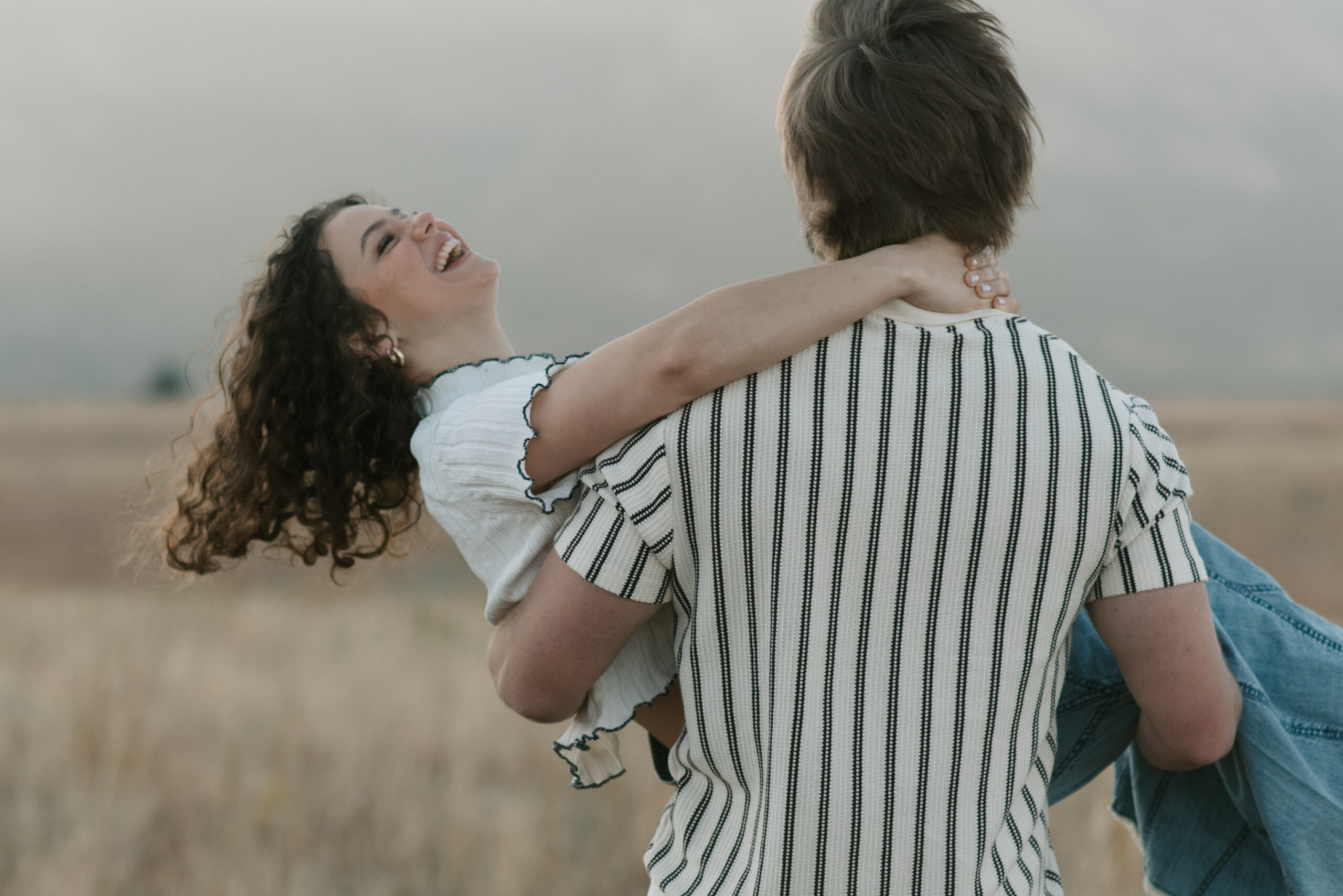 man carrying woman away from the camera and woman is laughing 
