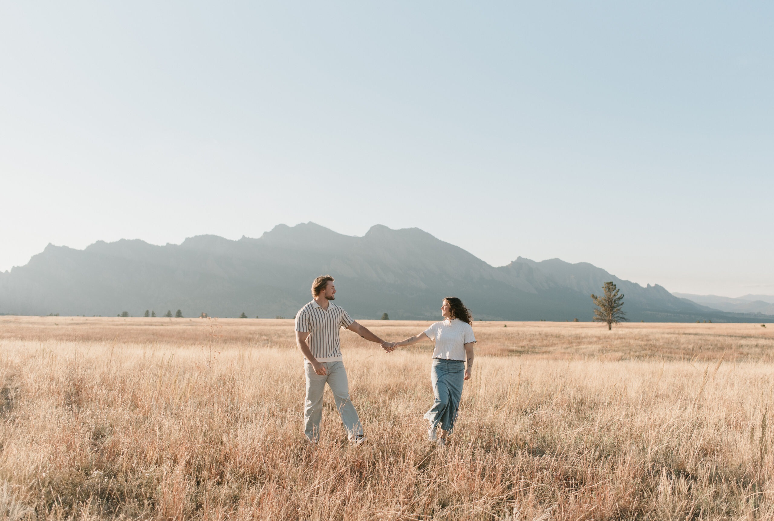 couple walking hand in hand through the dried grass during their couples photoshoot in colorado 