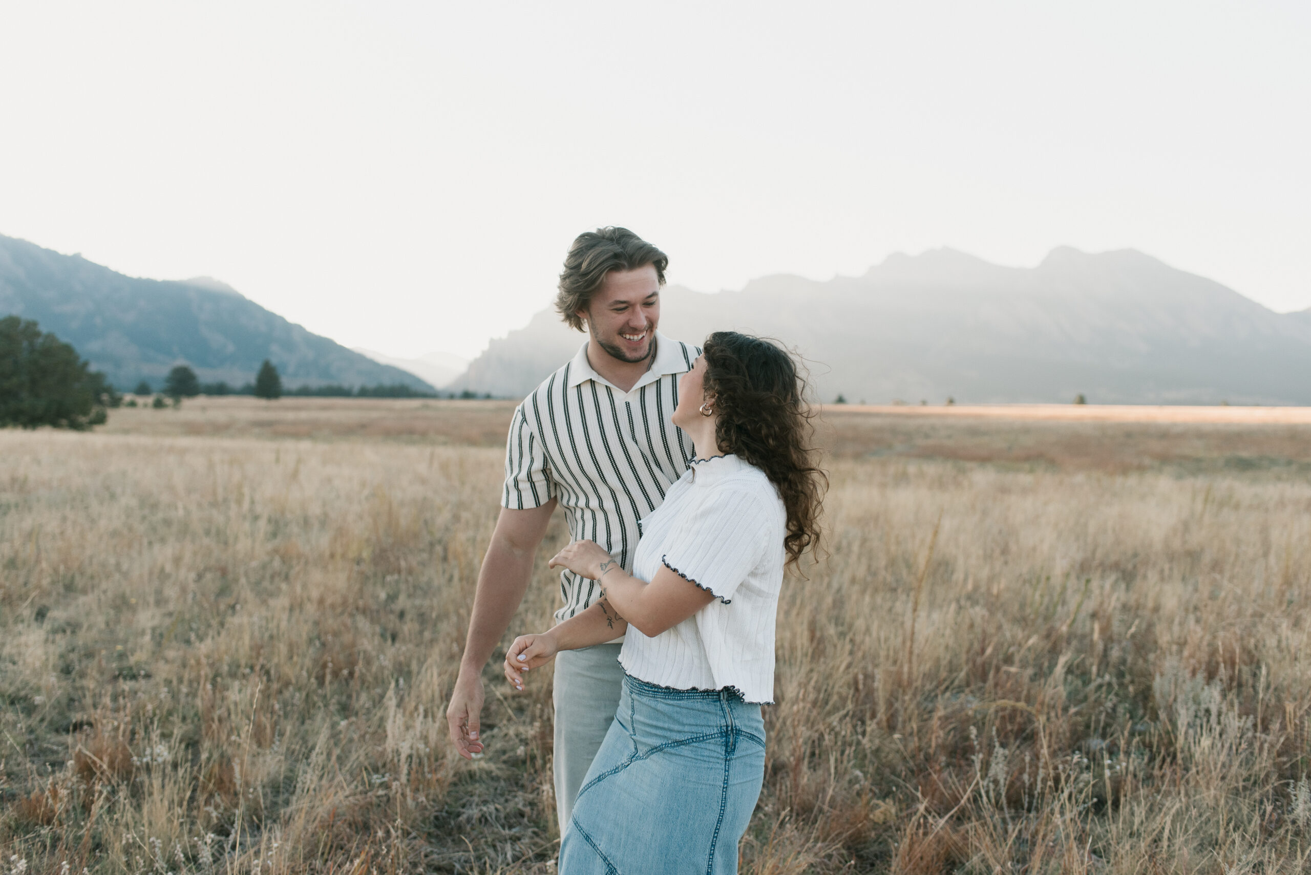 couple laughing with each other in a dried grass field during a couples photoshoot 
