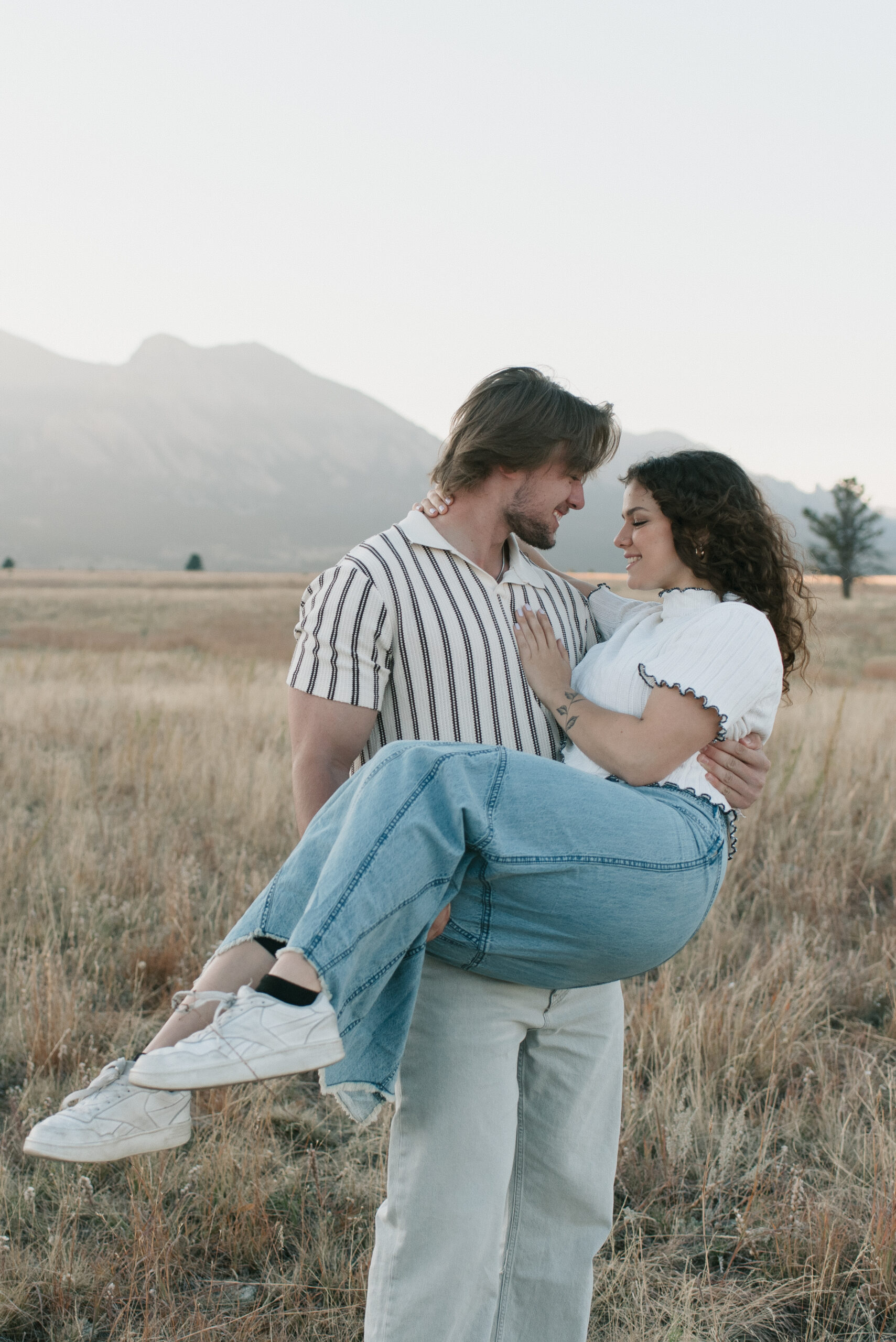man holding woman in the field during couple photoshoot 