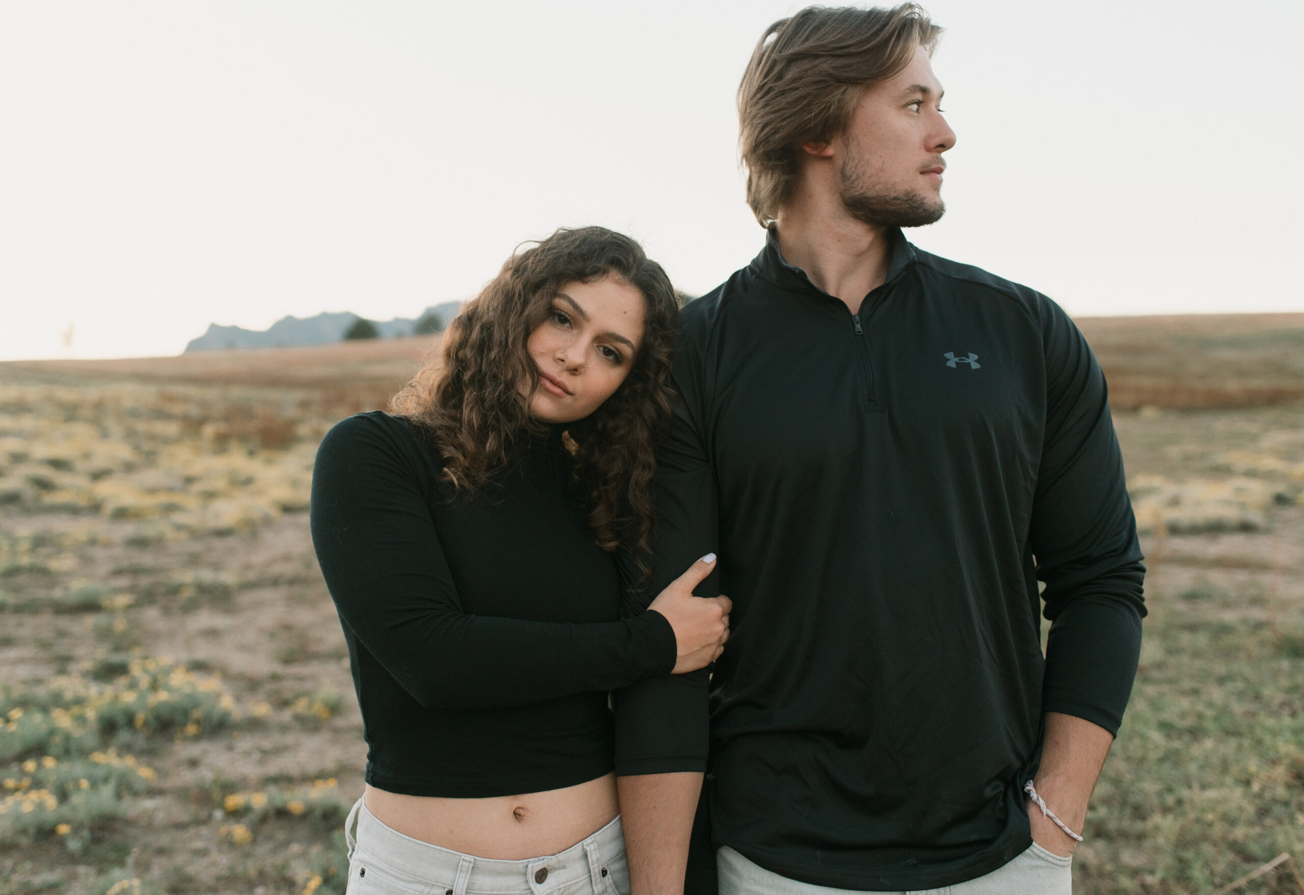 woman looking at the camera as she holds man's arm as he looks away during a couples photoshoot 
