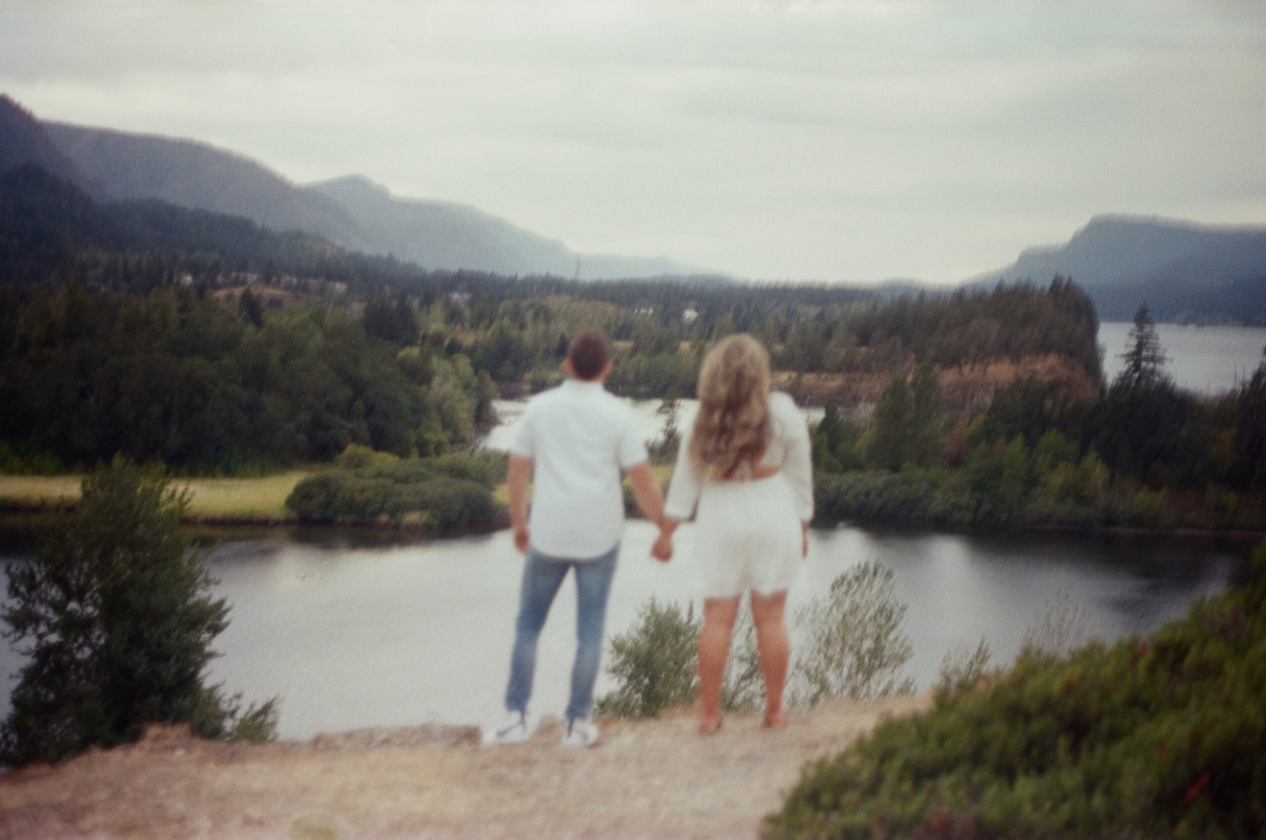 film photo of couple holding hands looking out at the view 