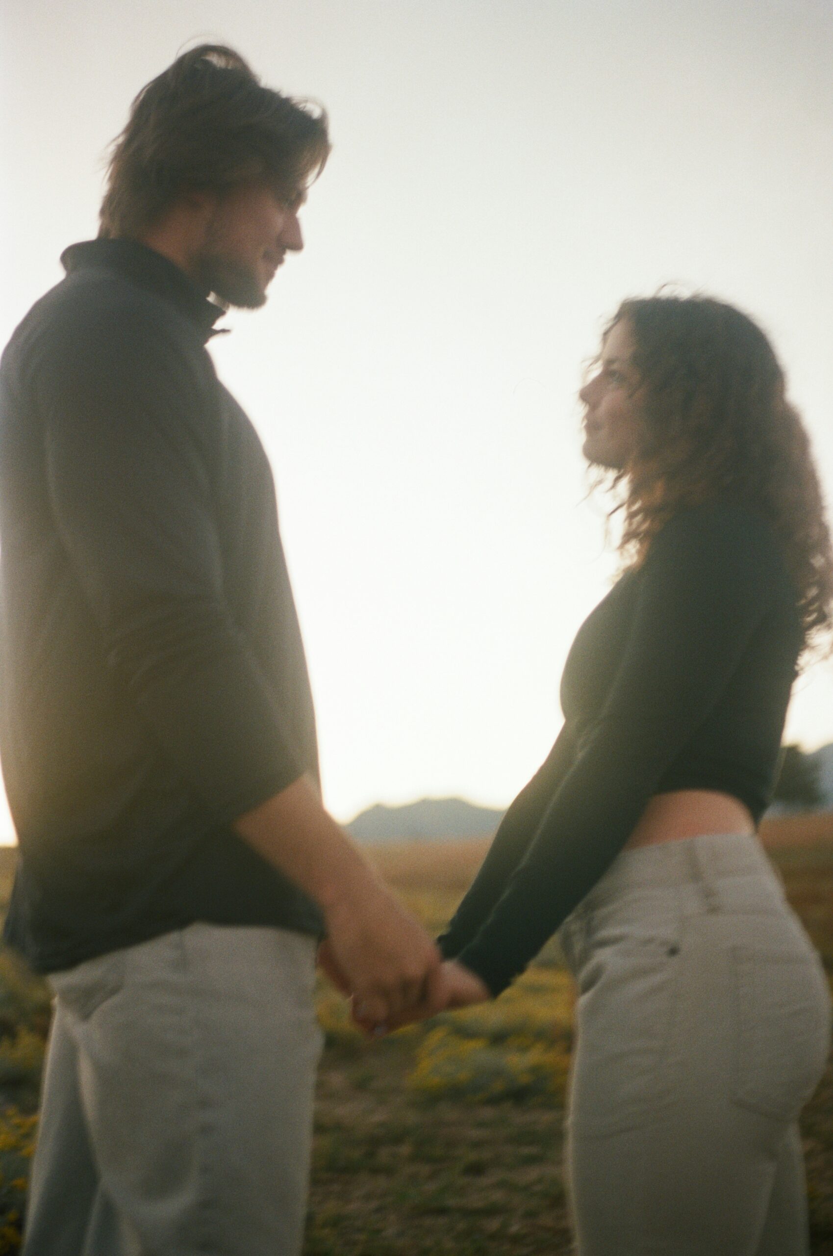 film photography of a couple holding hands and facing each other 