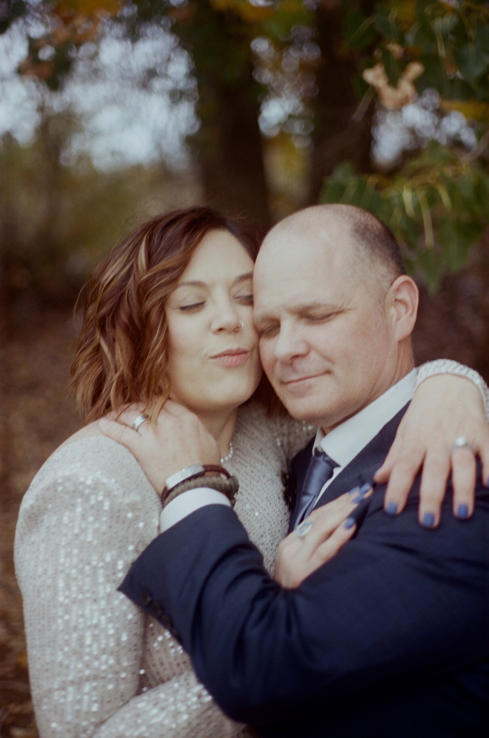 wedding film photography of a couple holding each other with their eyes closed, facing the camera