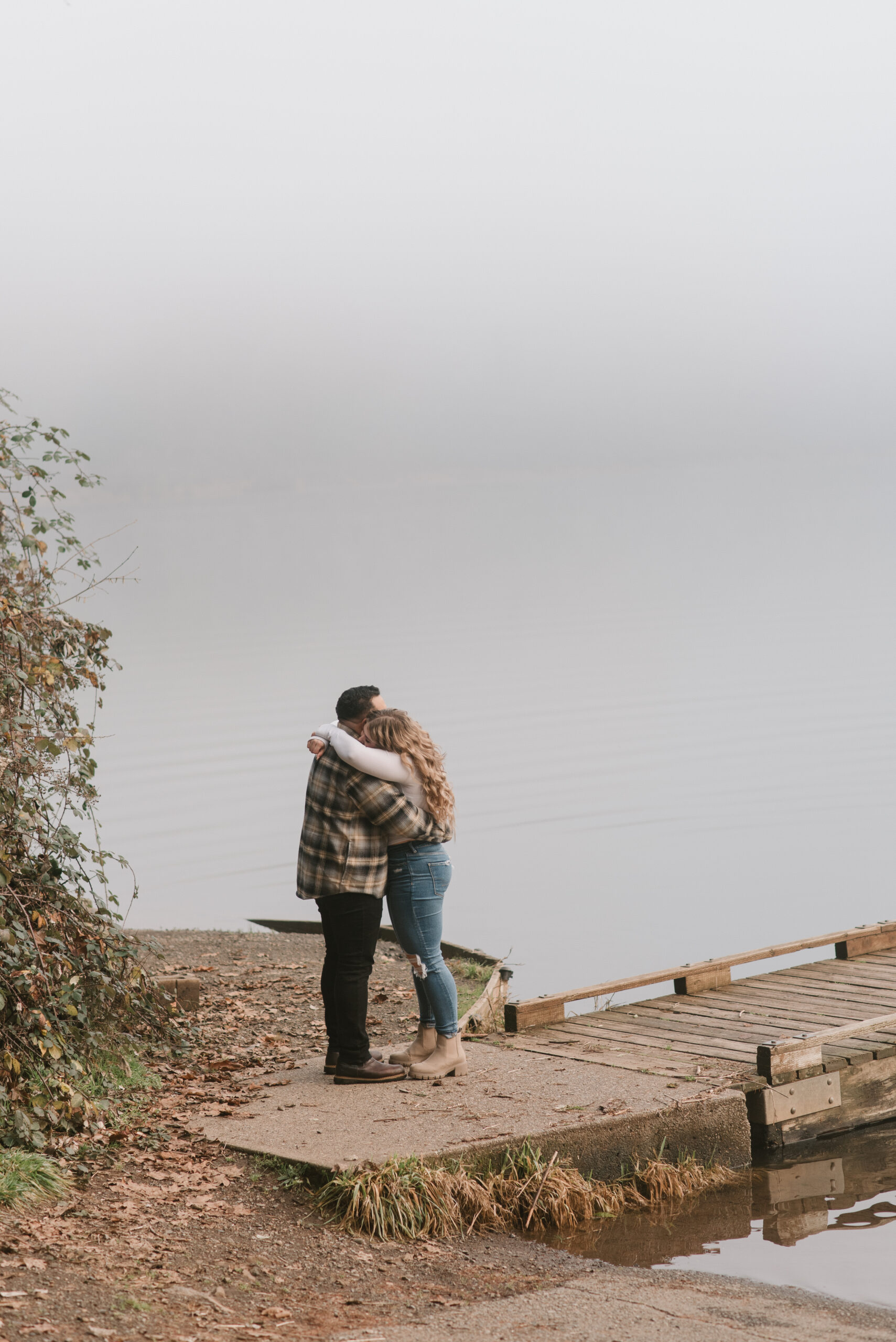a couple hugging by the lake in the fog captured by an Oregon engagement photographer 
