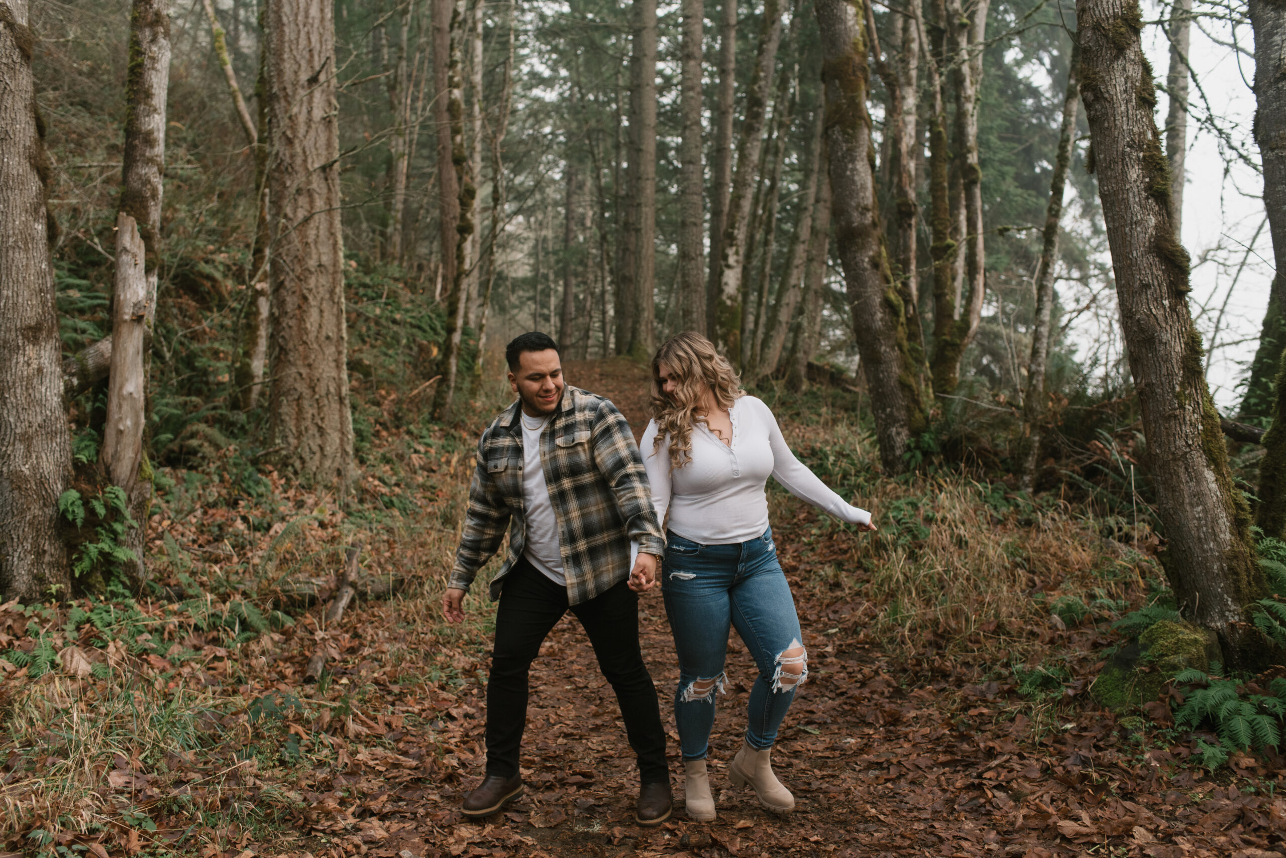 a couple walking and being playful in the forest captured by an Oregon engagement photographer 