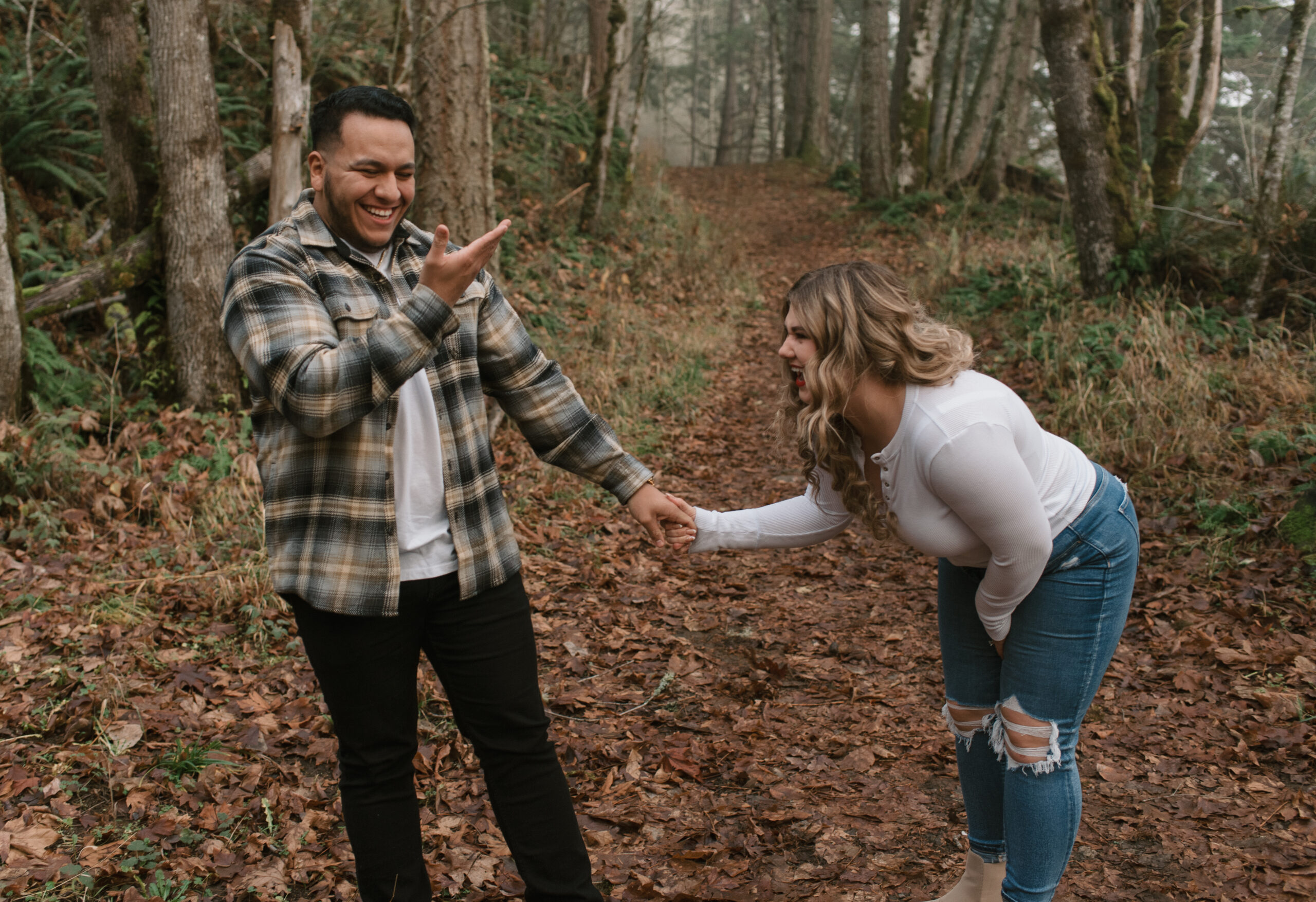 an engaged couple laughing and being playful in the forest captured by an Oregon engagement photographer 