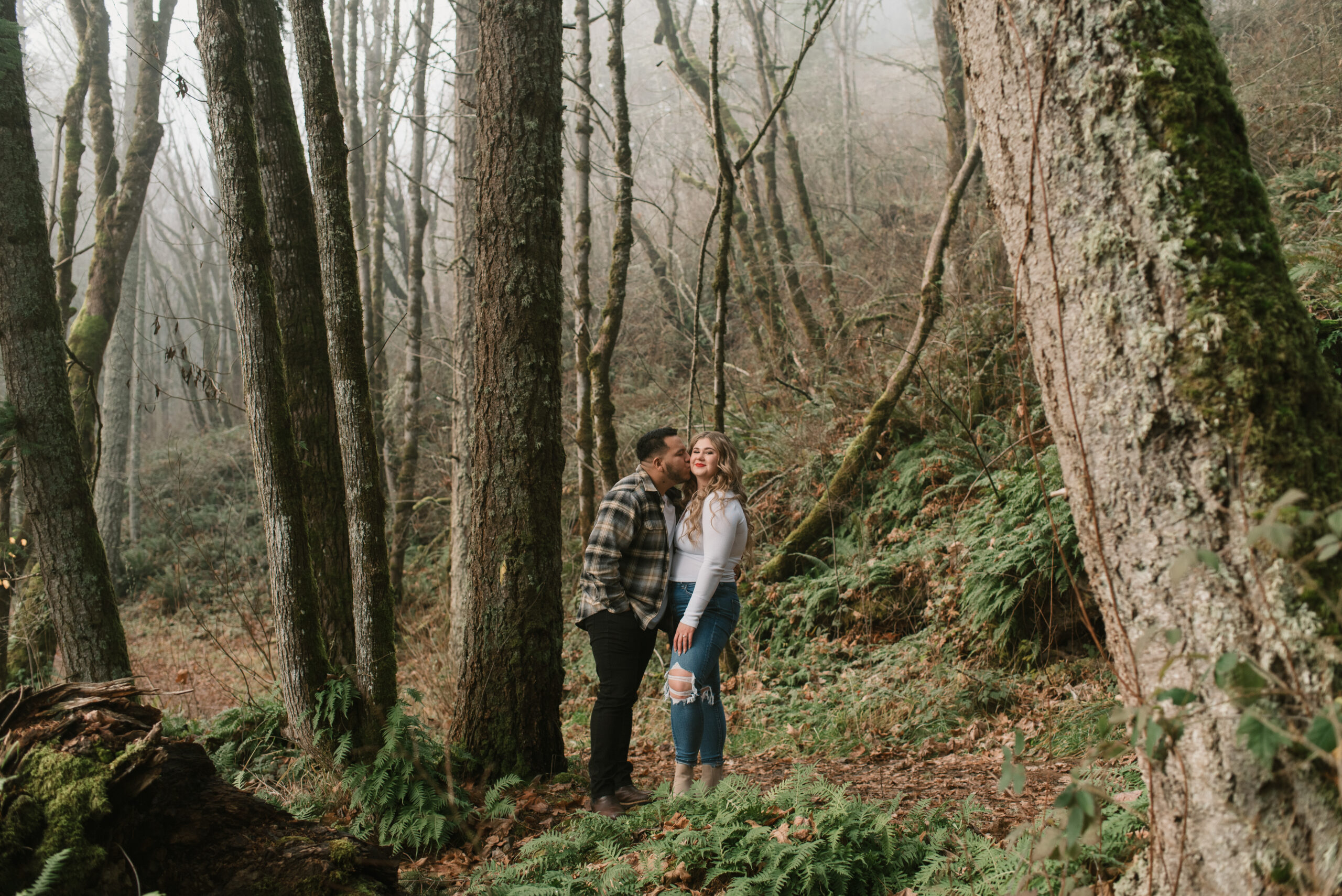 fiance kissing other fiances cheek in the forest 
