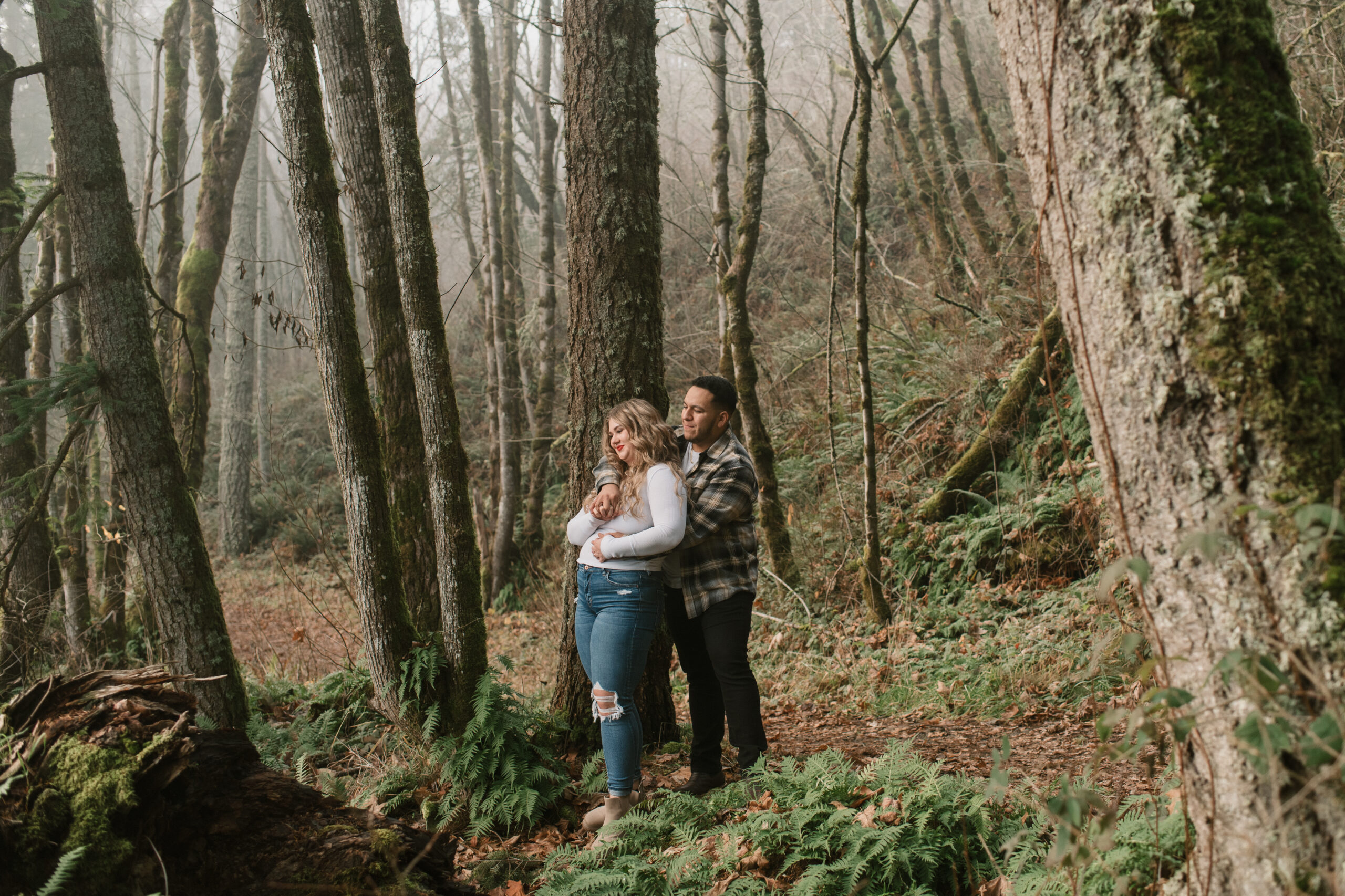 a couple holding each other while standing in a foggy forest in Oregon 