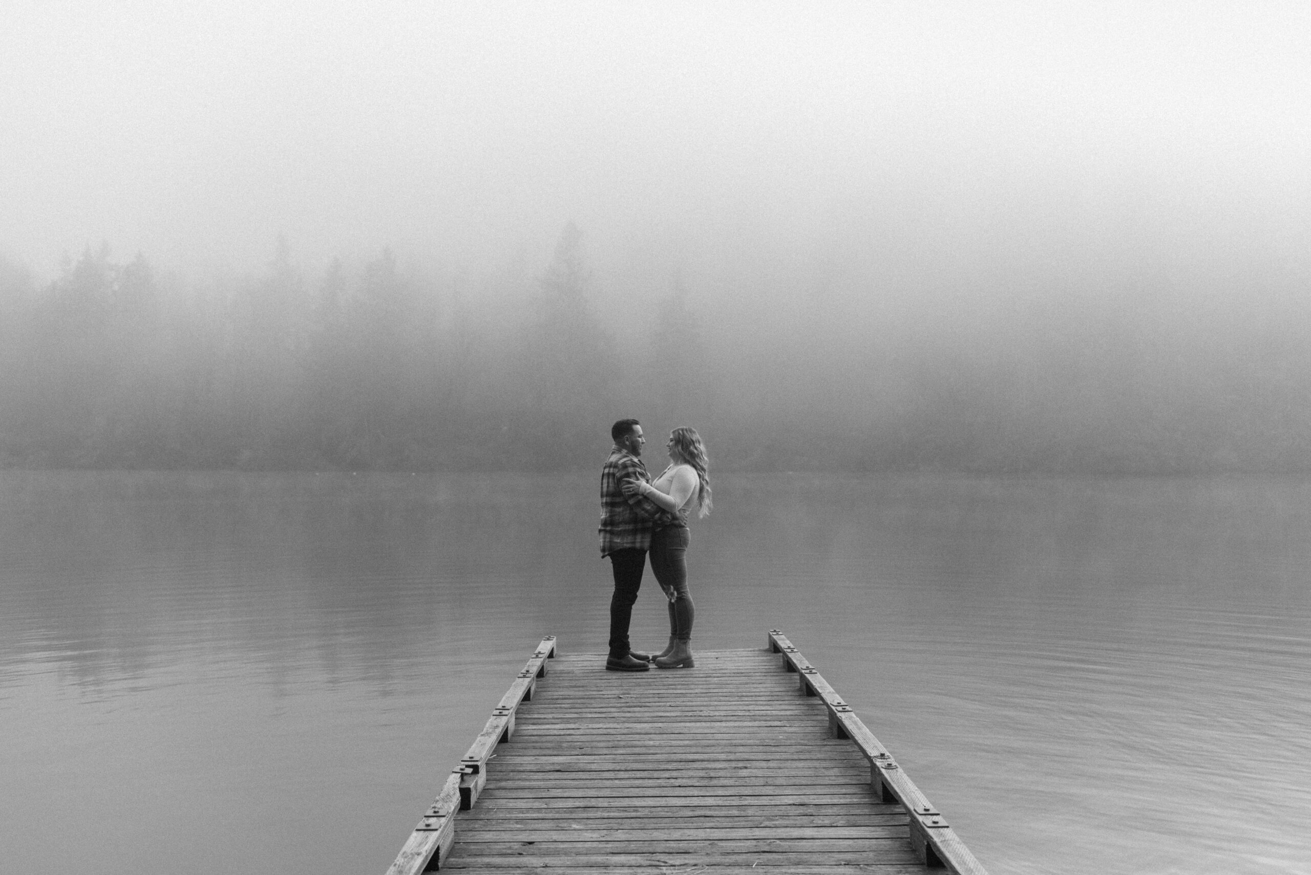 newly engaged couple hugging on a dock 