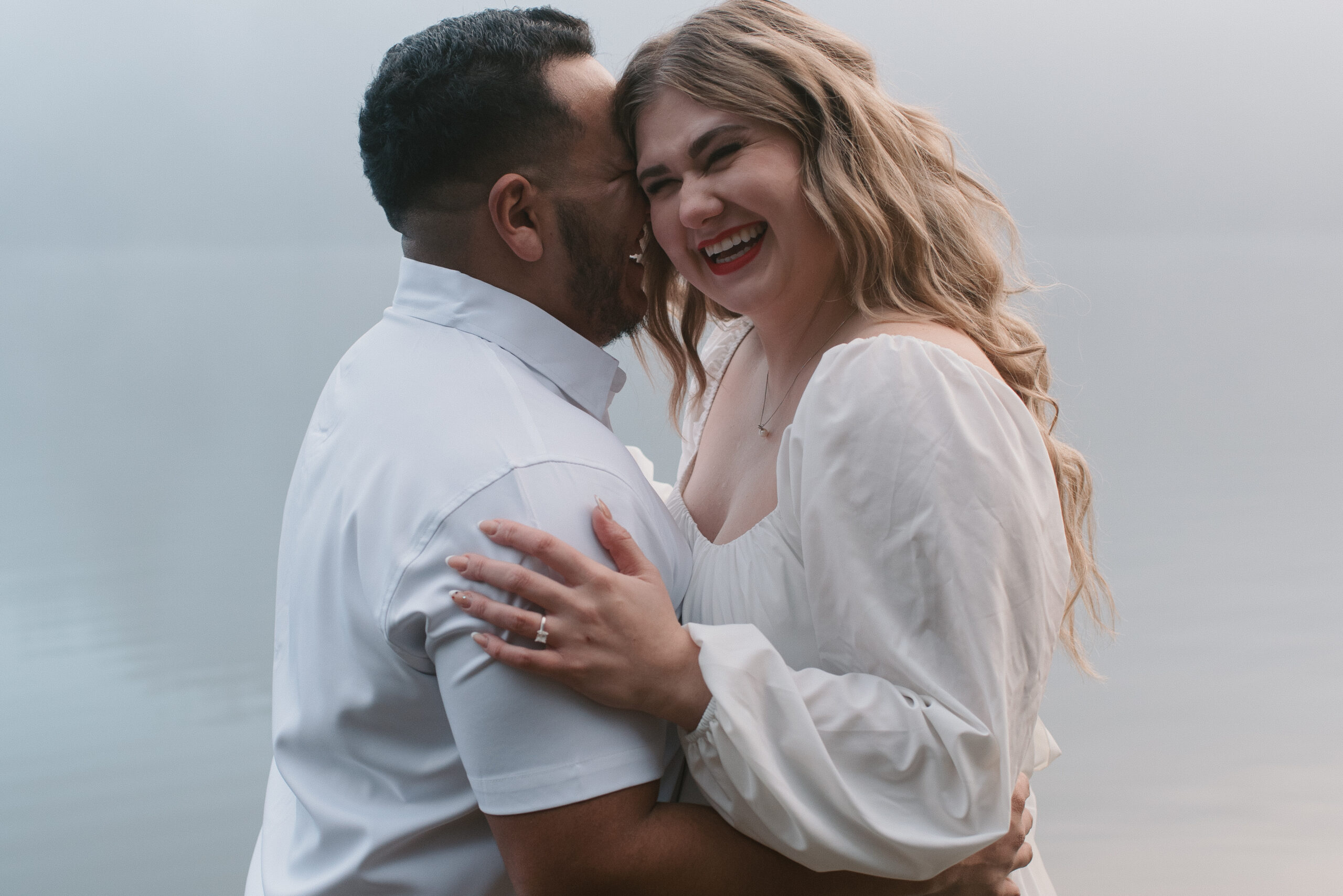 a couple laughing and holding each other in the fog captured by an Oregon engagement photographer 