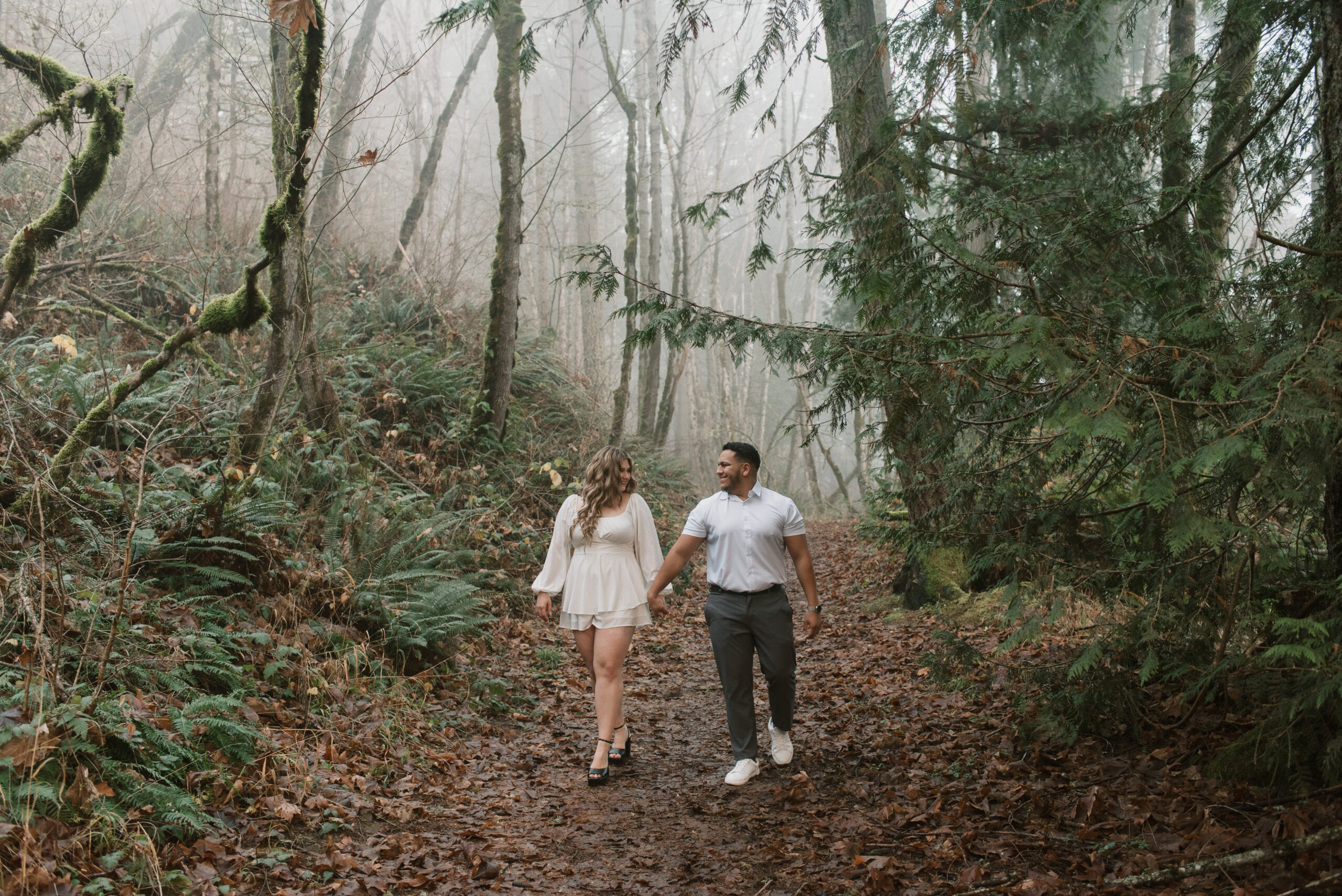 a couple walking in a foggy forest captured by an Oregon engagement photographer 