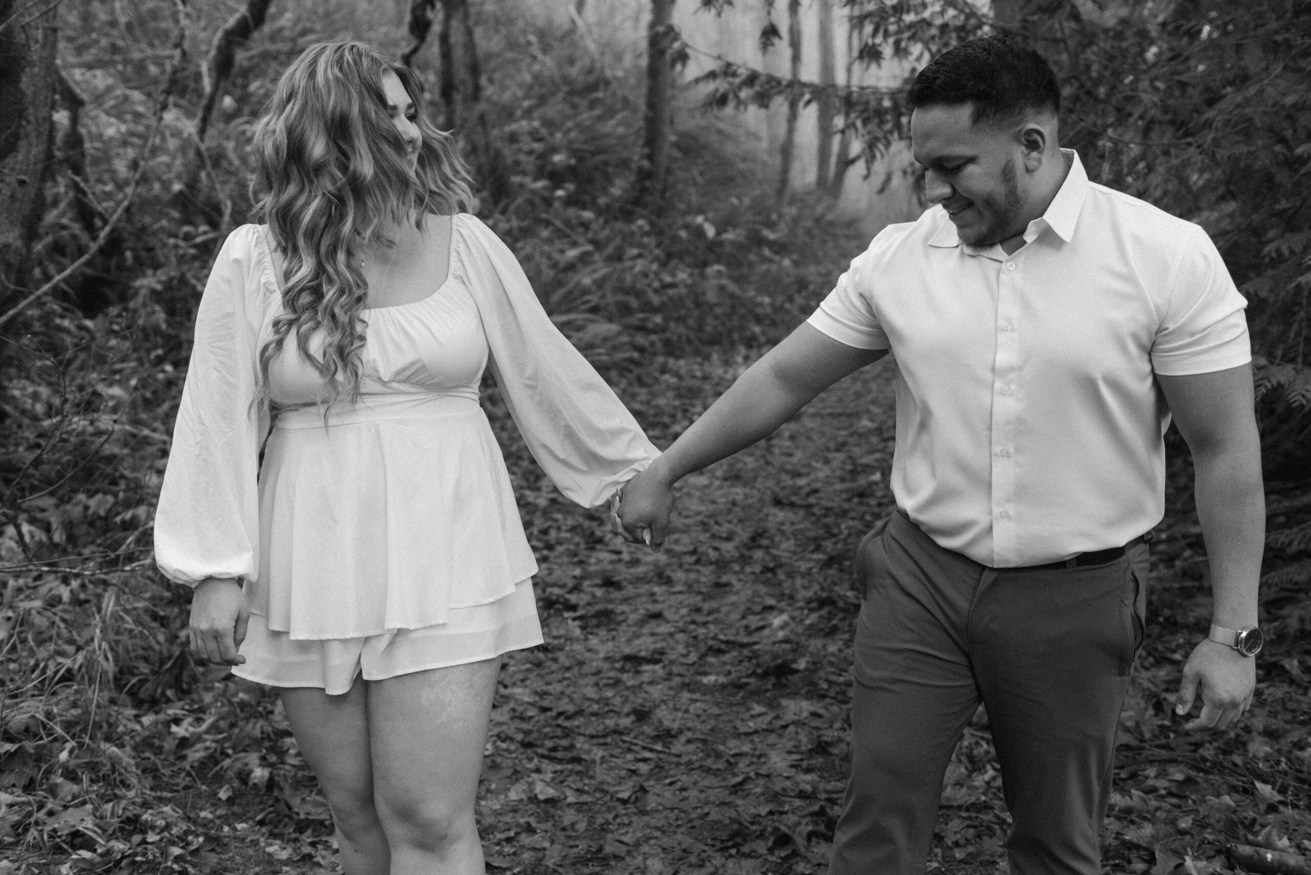 newly engaged couple holding hands and walking through a forest