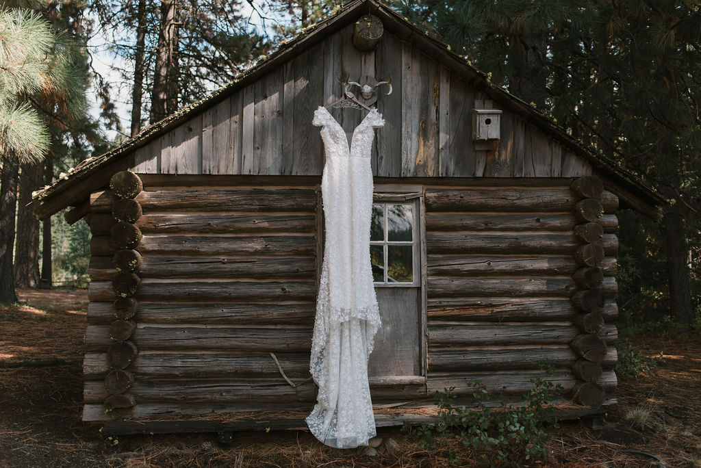 bride's dress hanging on a log cabin