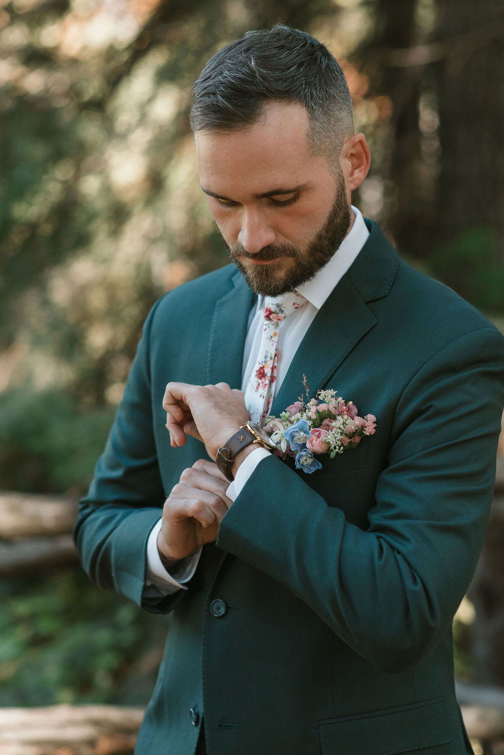 groom portrait, wearing a teal suit, showing their personalized wedding details