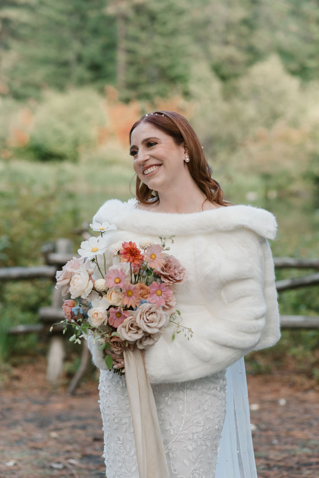 bride wearing a fur coat and smiling with her whimsical bouquet 