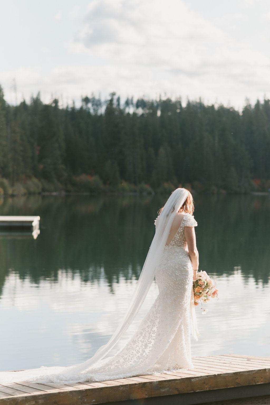 bride standing on the dock with the water reflecting behind her 
