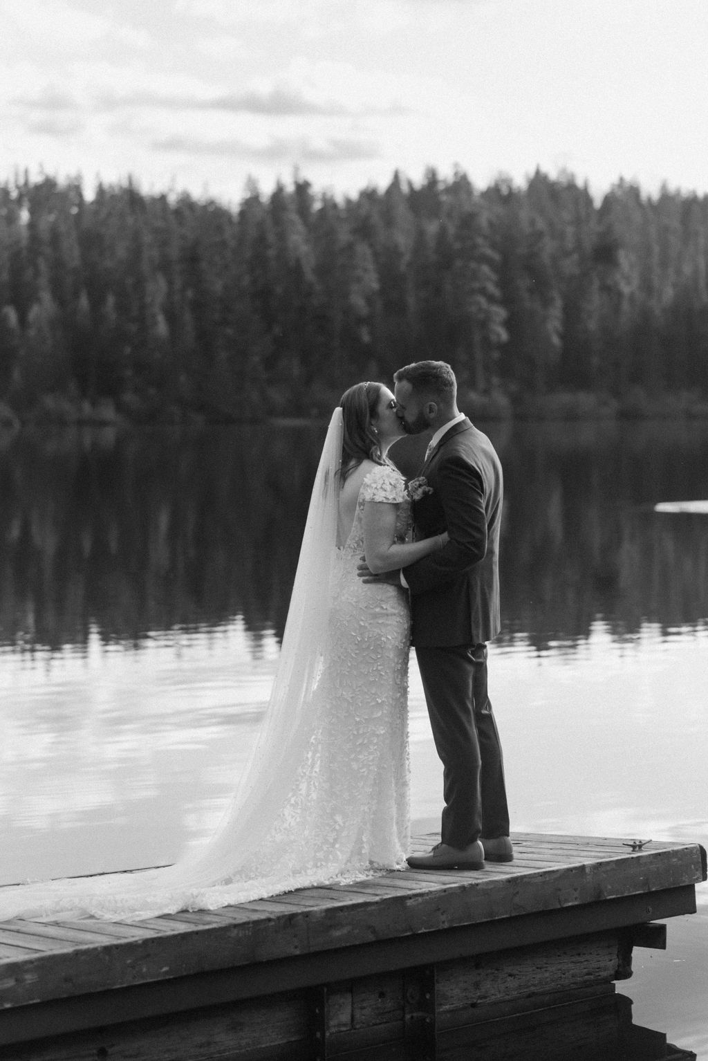 black and white of bridal couple kissing on the dock 