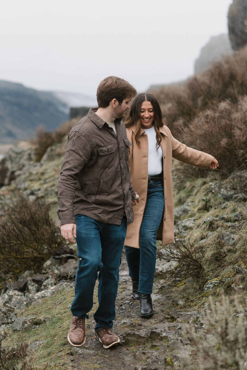newly engaged couple, holding hands and walking on a trail for their modern engagement pictures