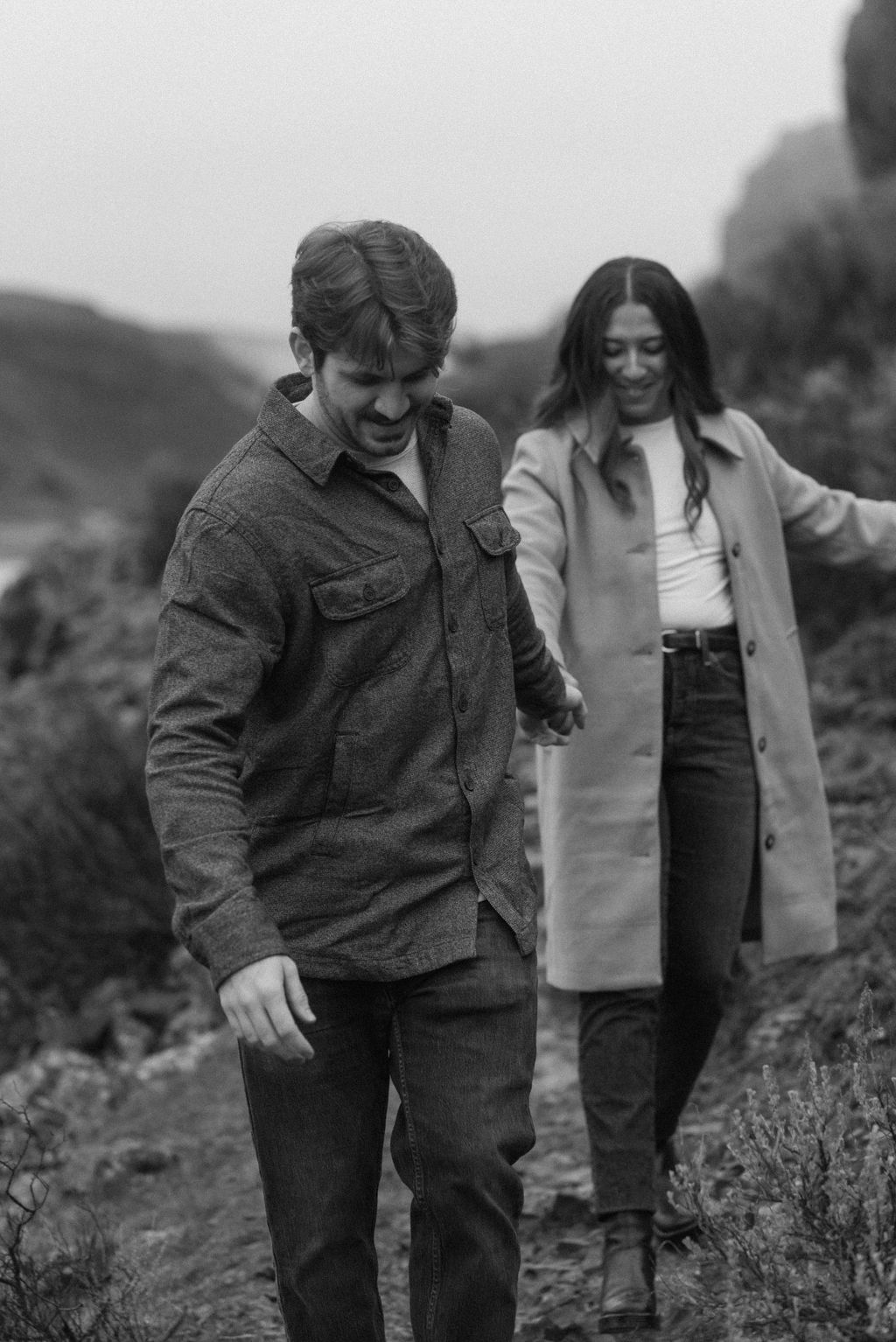 black and white of newly engaged couple walking down a path together during their modern engagement pictures