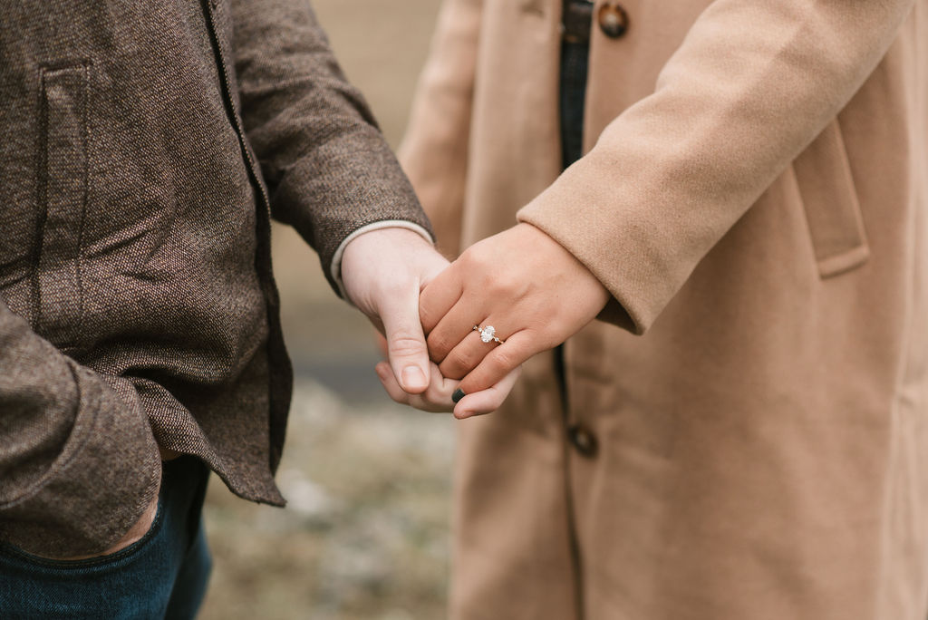 close up of engaged couple holding hands and the engagement ring 