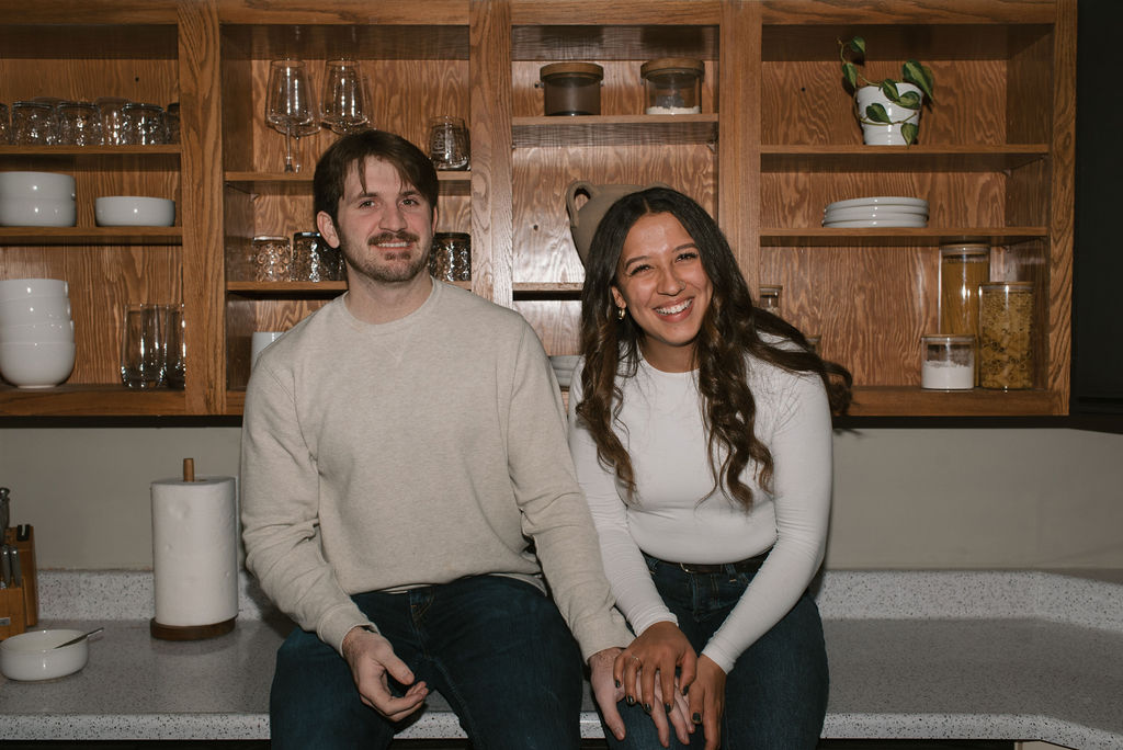 newly engaged couple sitting on the counter and laughing 