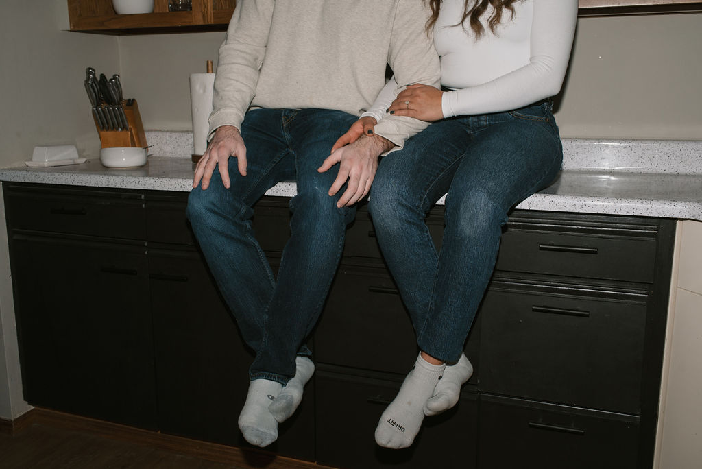 couple sitting on the kitchen counter holding hands 