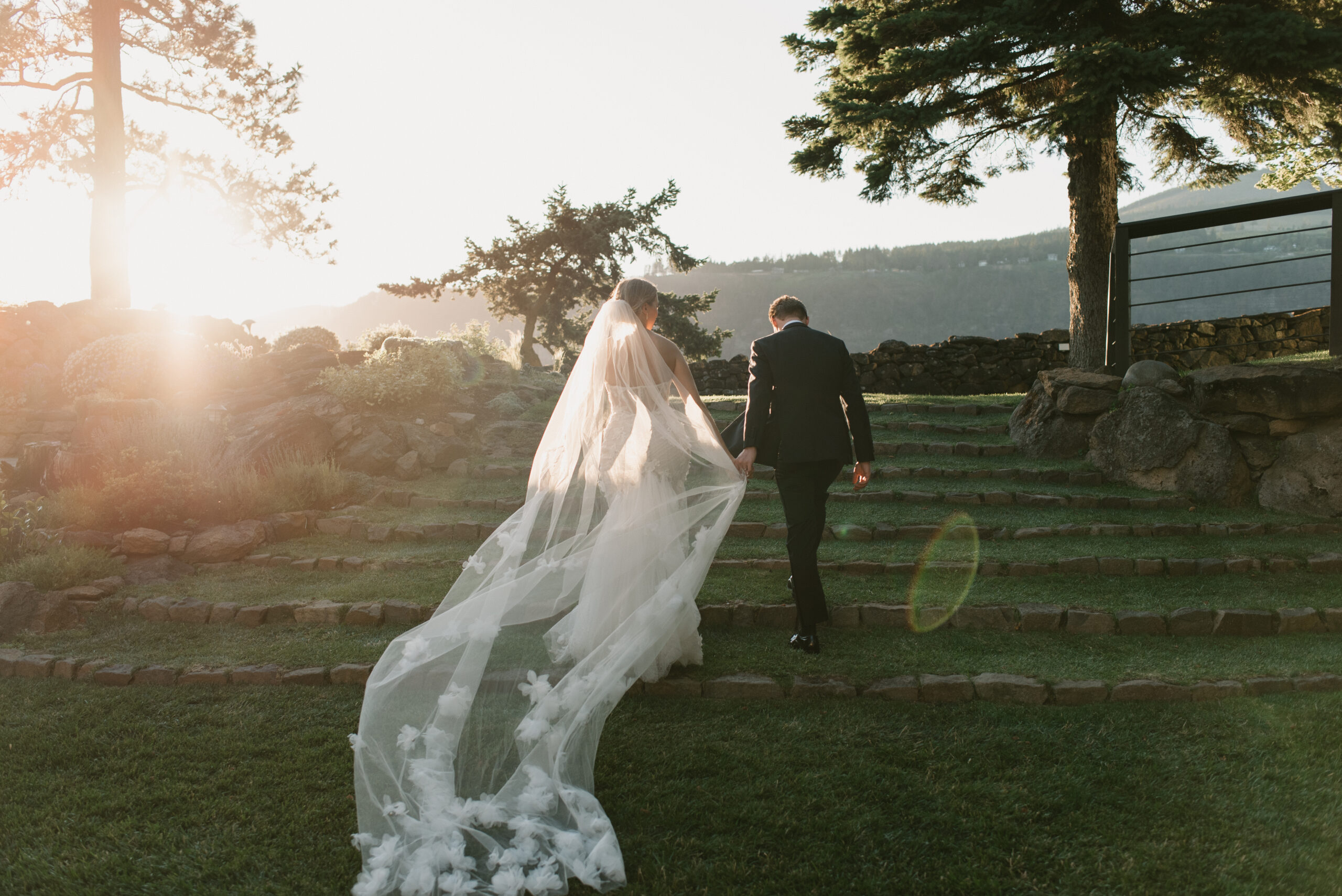 the bride and groom walking up the stairs together at sunset at the griffin house