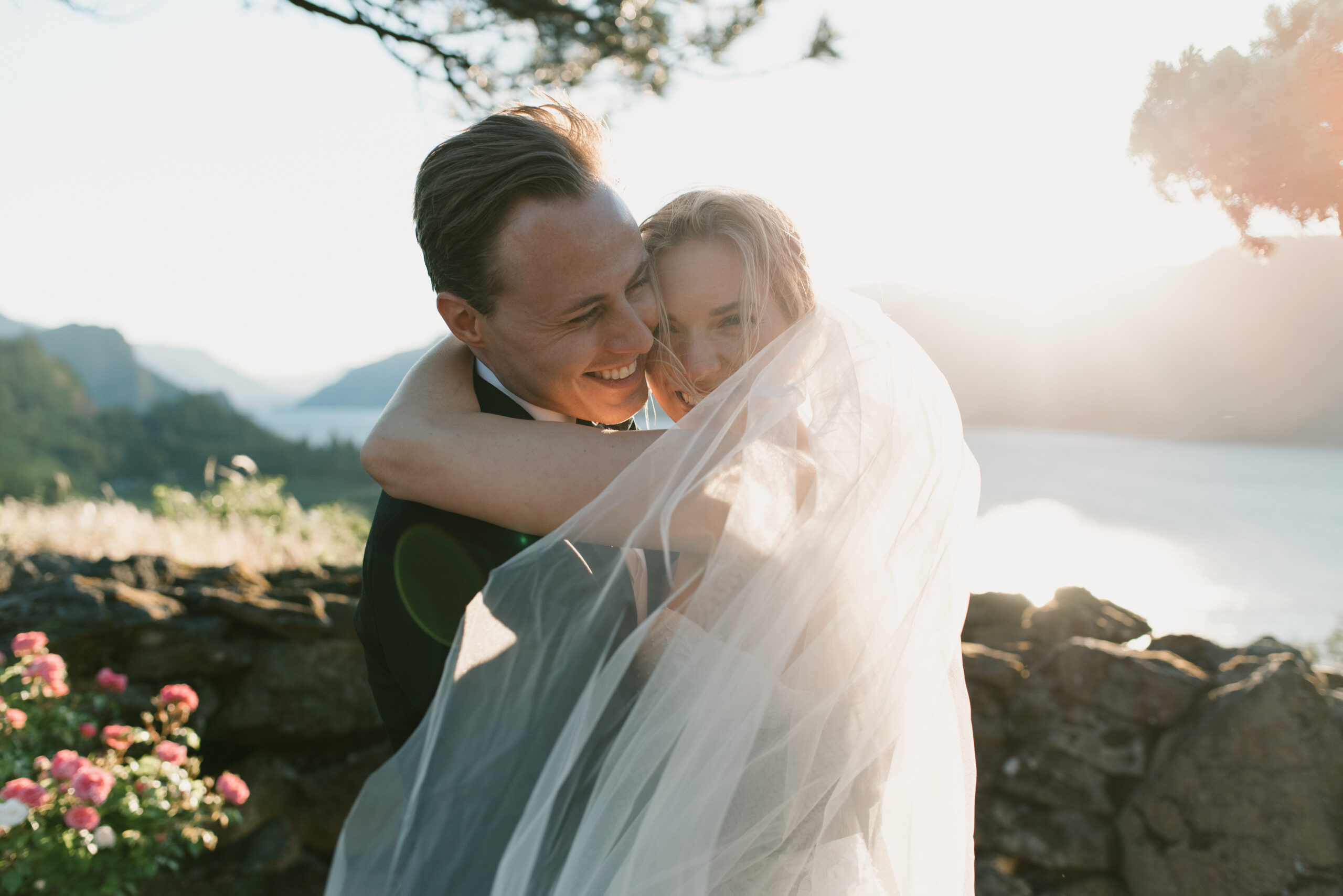 the bride and groom laughing while hugging at sunset