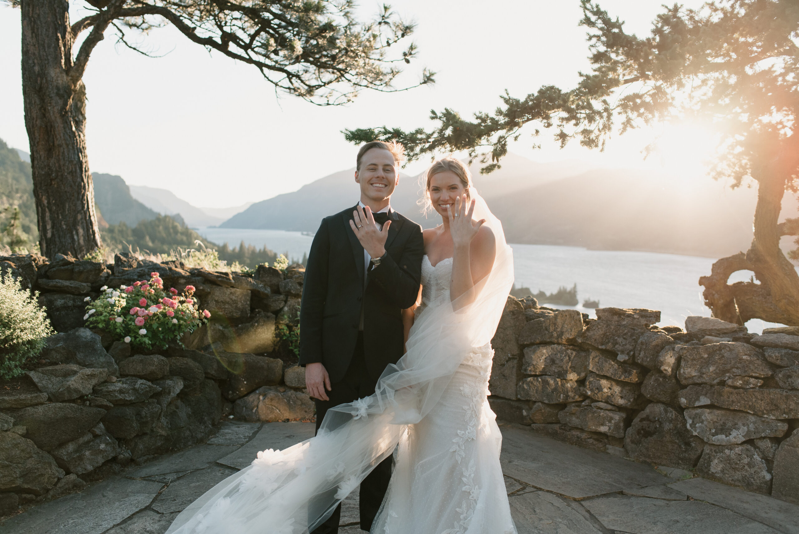 bride and groom showing off their new wedding rings at sunset