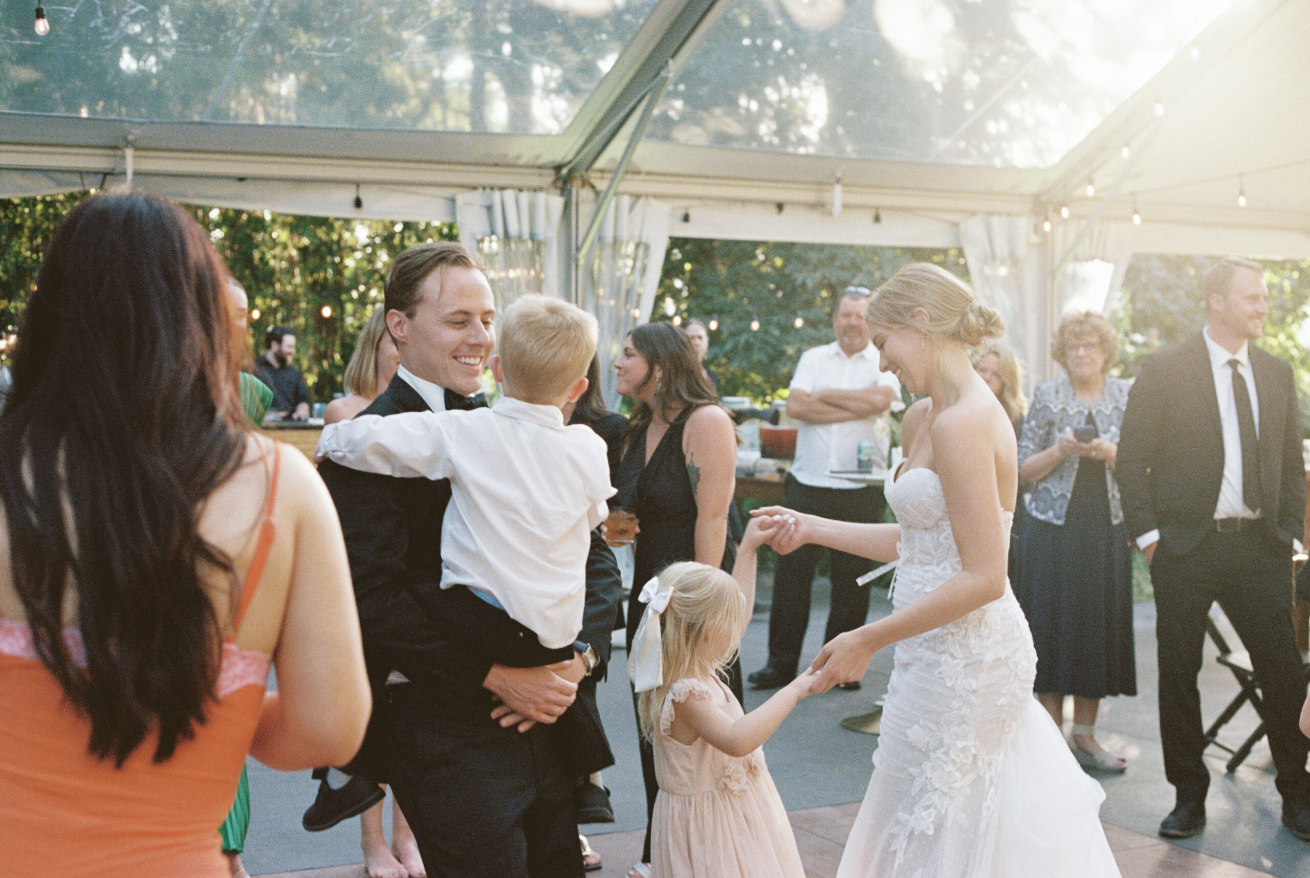 a film photo of the bride and groom dancing with children at the griffin house