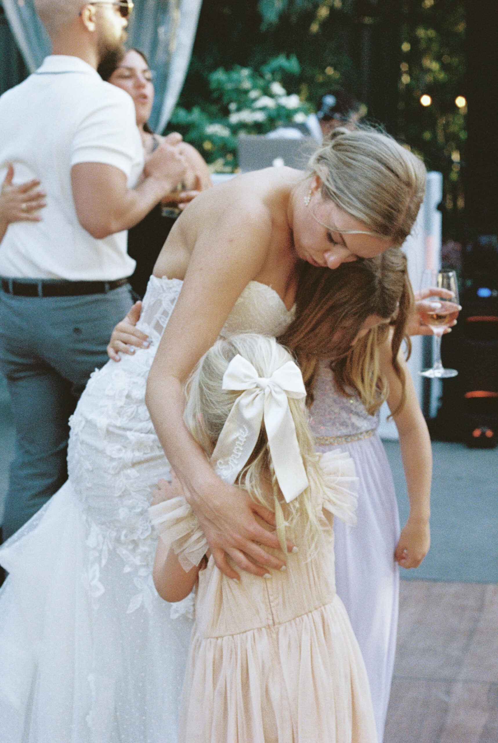 a film photo of the bride hugging her nieces while on the dance floor