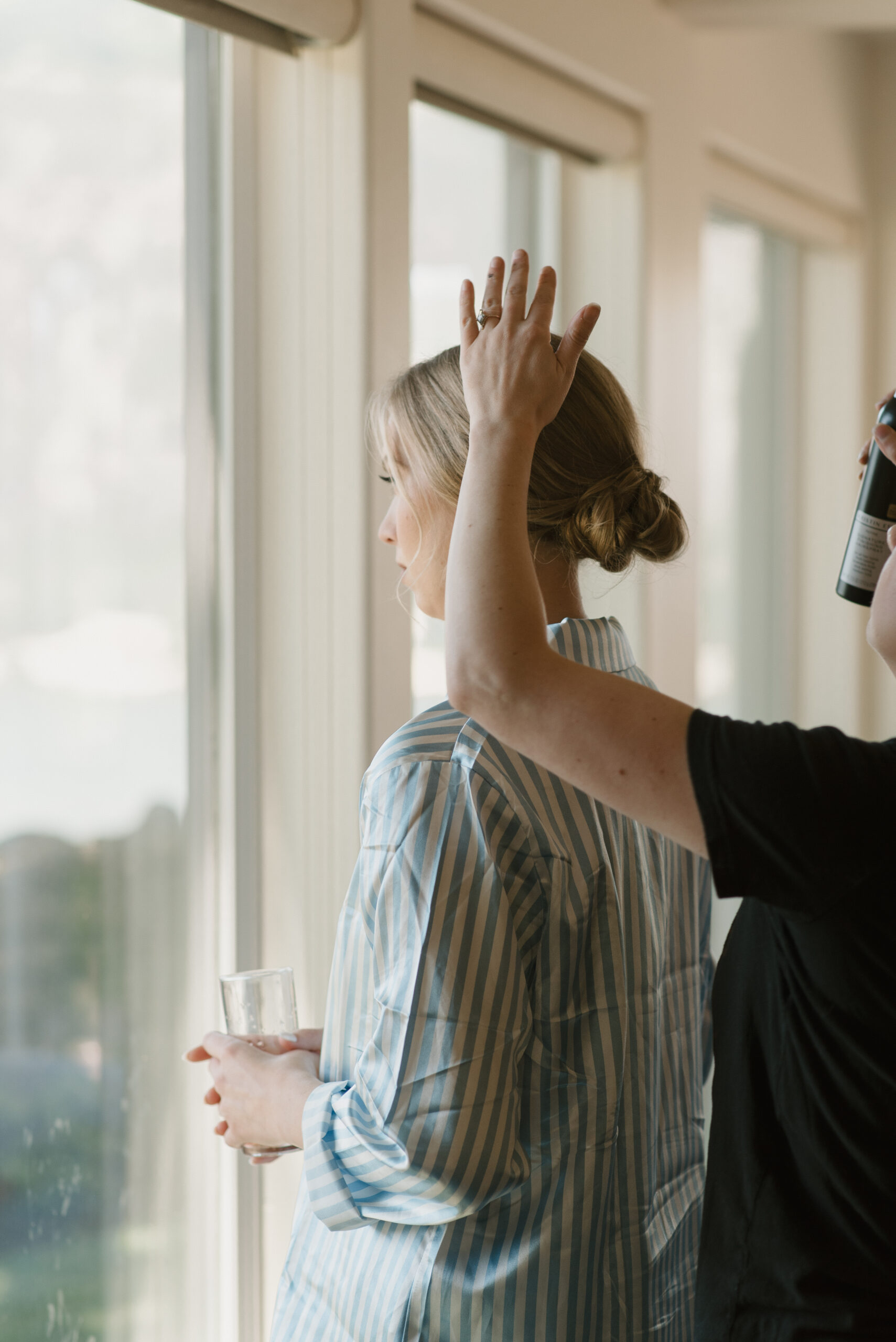 Bride getting her hair sprayed while getting ready for her wedding