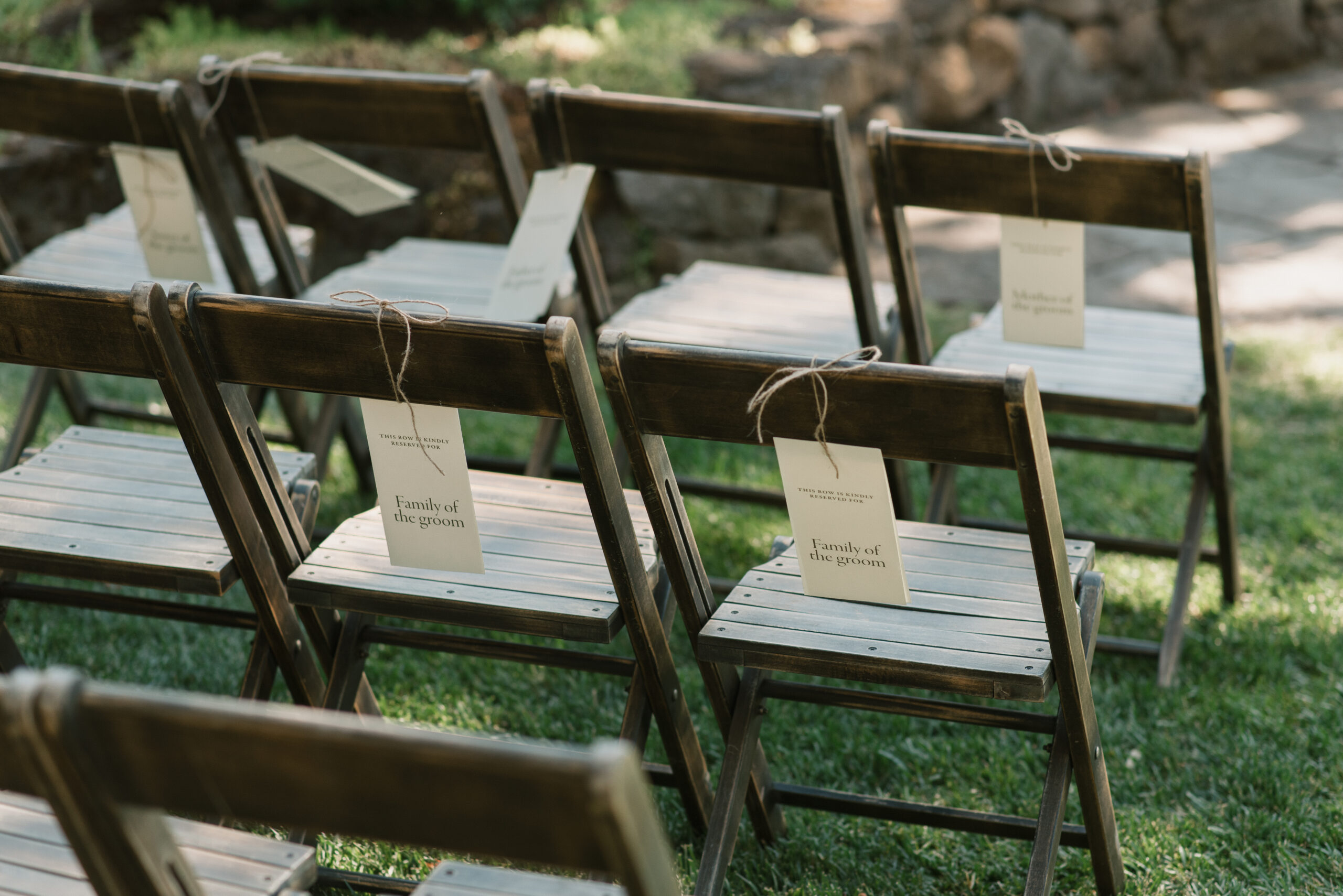 Beautiful wooden chairs with reserved seating signs for the family of the couple