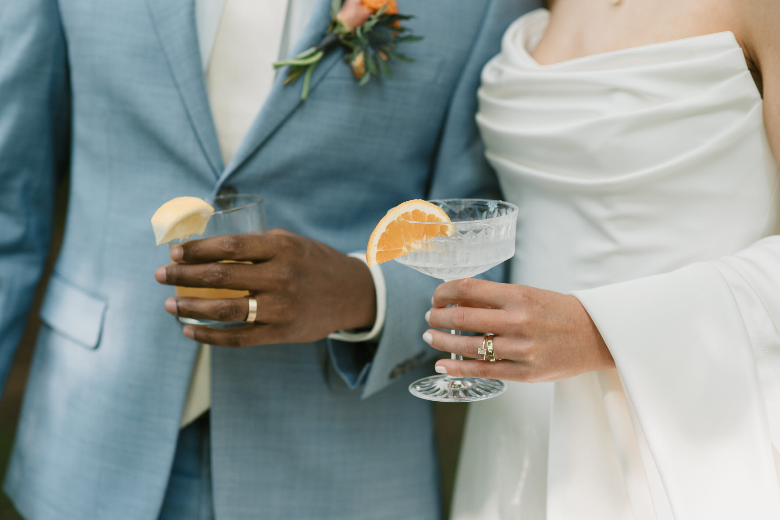 bride and groom holding their signature cocktails and showing off their new wedding bands