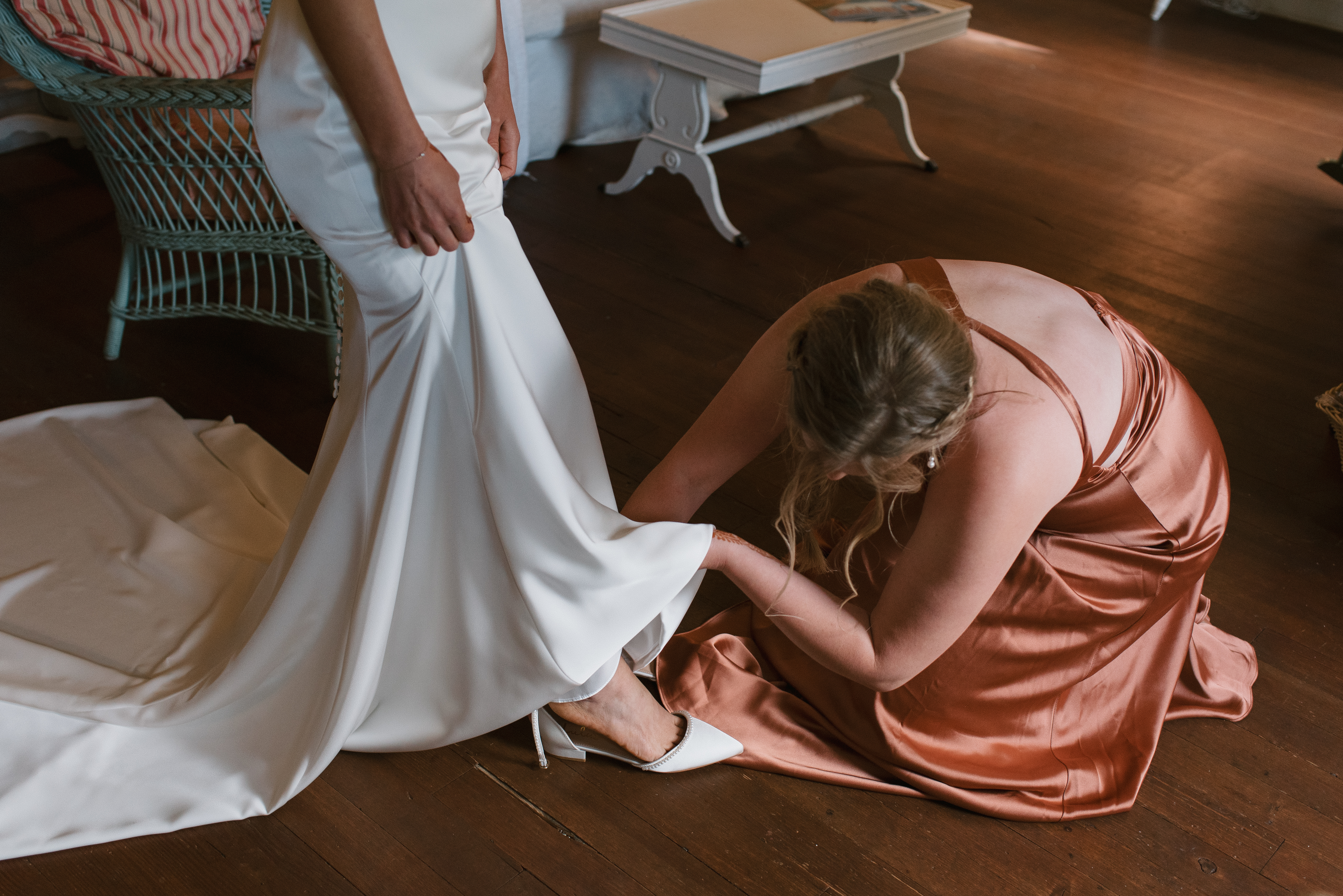 the sister of the bride helping her put on her shoes